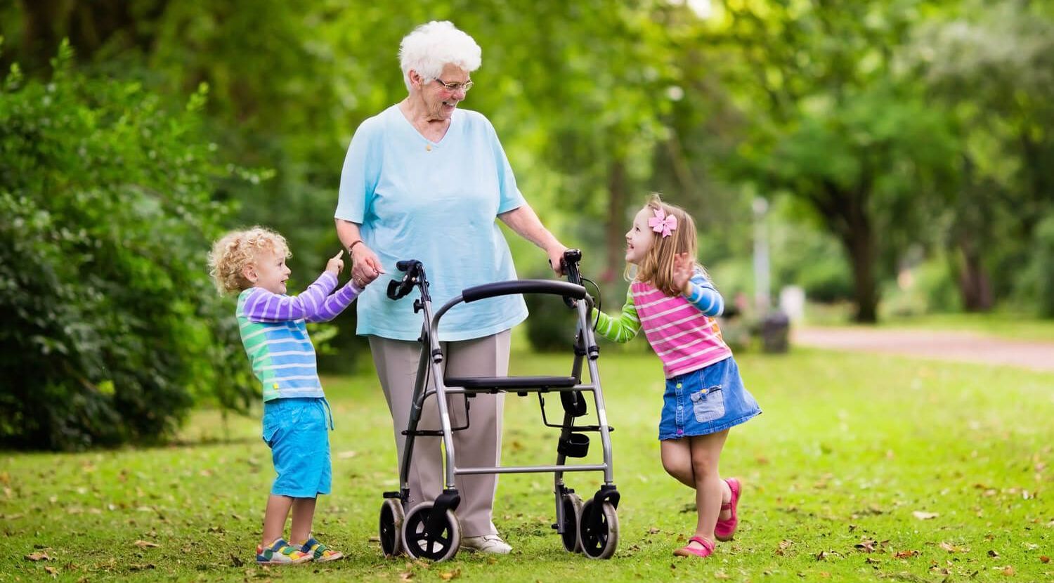 Foto einer älteren Frau an einem Rollator, die fröhlich mit zwei Kindern spielt Foto einer älteren Frau an einem Rollator, die fröhlich mit zwei Kindern spielt