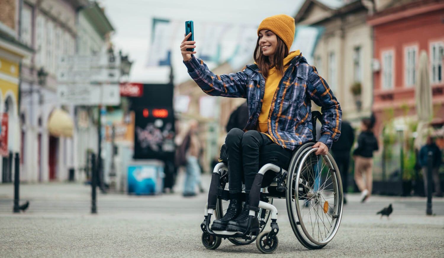 Foto von einer jungen Frau, die im Rollstuhl sitzt und ein Foto von sich selbst macht