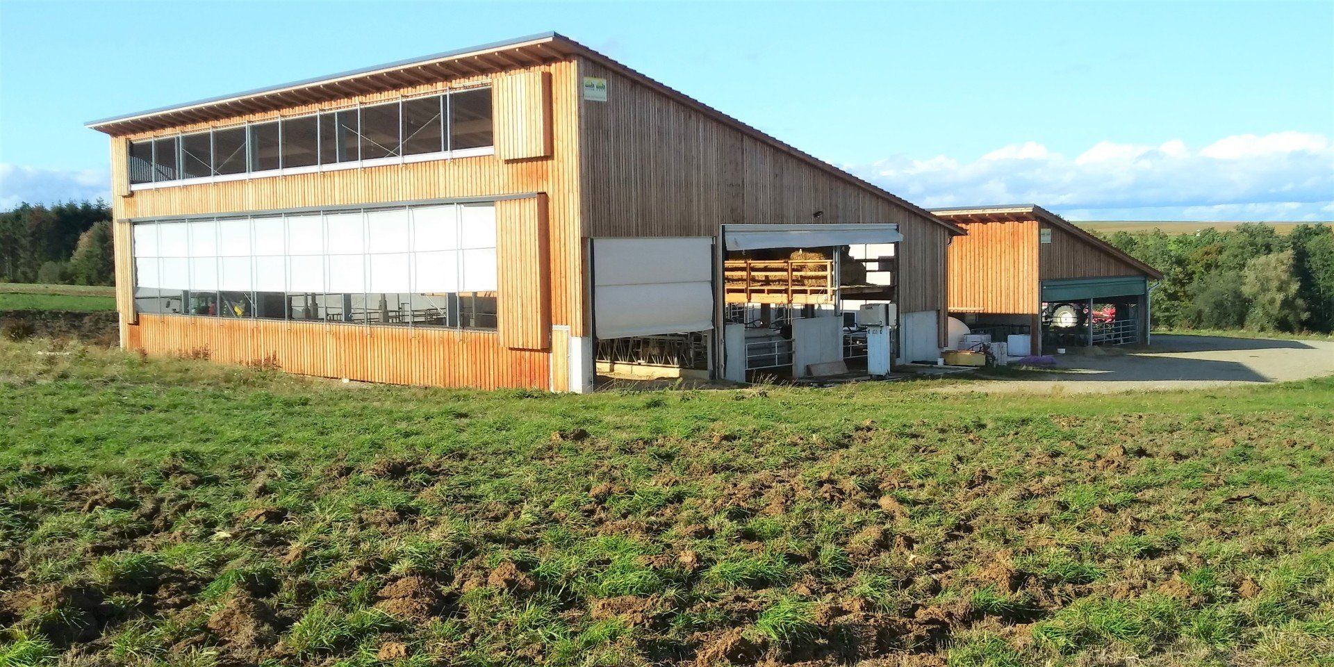 Neubau Milchviehstall Der Stallneubau bietet den Kühen idealen Kuhkomfort. Der Special Needs Bereich ist mit einer Abkalbebox und einer Cuddlebox ausgestattet. Die Strohbühne erleichtert das Einstreuen enorm. Im seperaten Melkhaus ist ein Sidebyside Melkstand untergebracht. Durch die Pultdachkonstruktion ist eine Erweiterung leicht möglich.