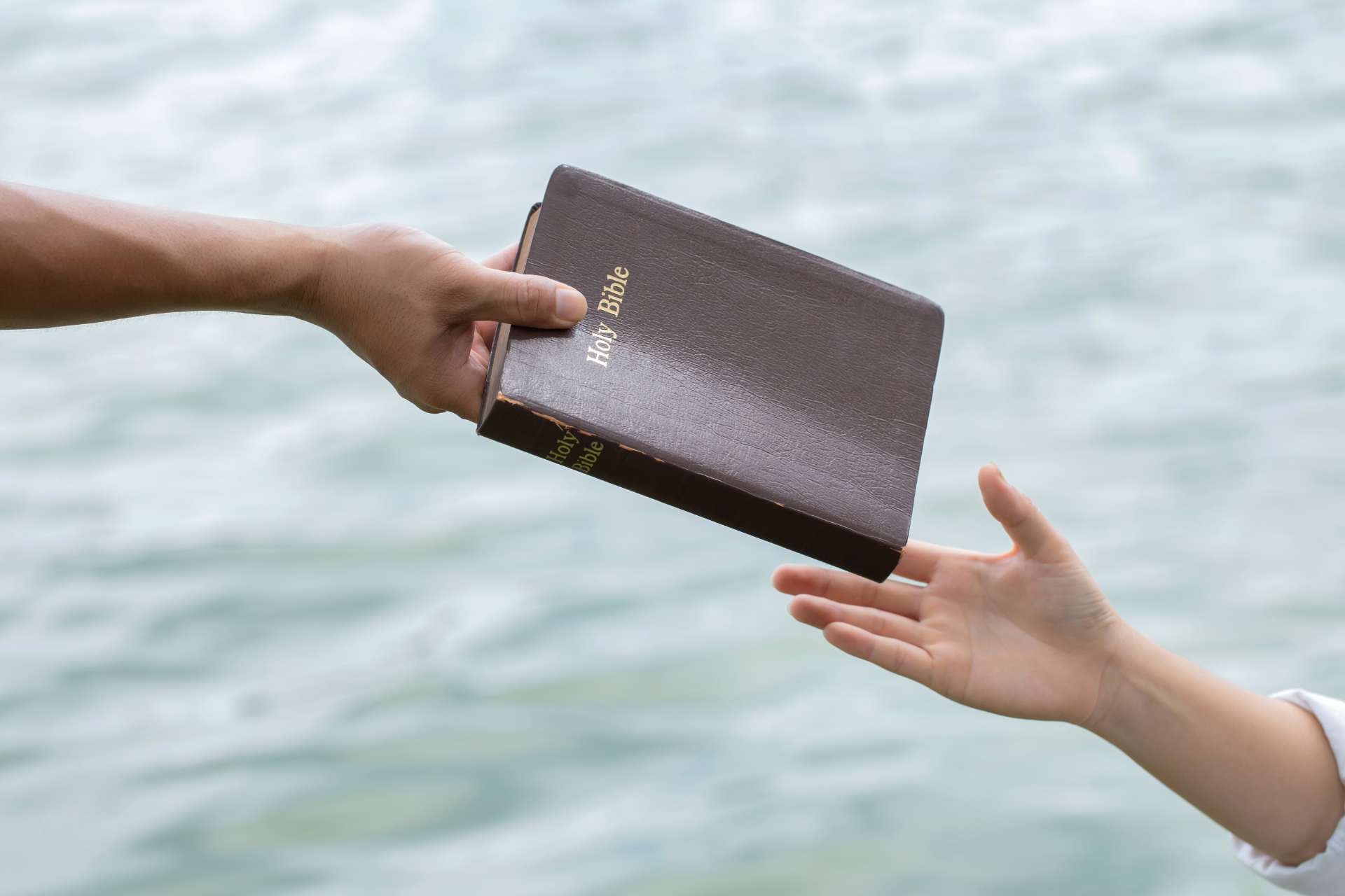 a person passing a bible to another person