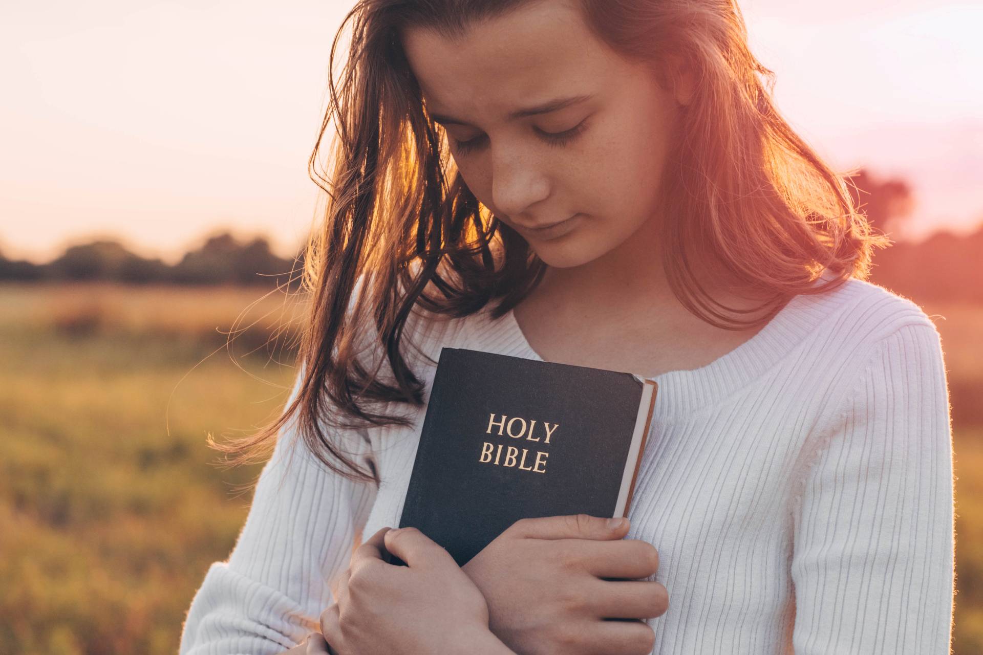 a young girl holding a bible to her chest