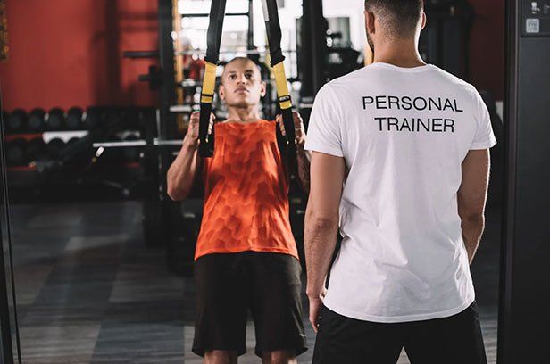 Erste-Hilfe-Kurs für Trainer Personal Trainer trainiert einen Mann am TRX
