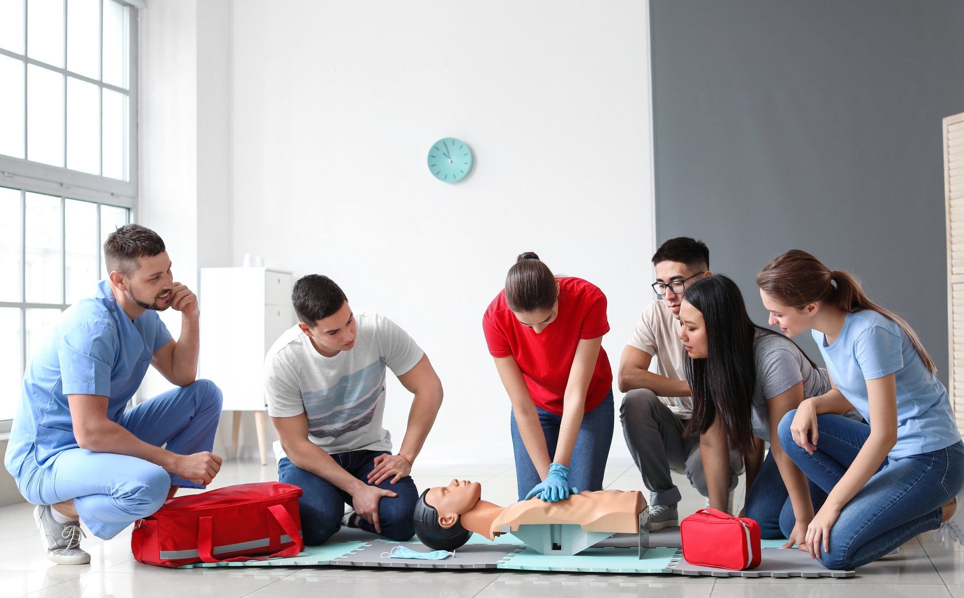 Herz-Lungen-Wiederbelebung Herz-Lungen-Wiederbelebung wird von einer Erste-Hilfe-Trainerin im Erste-Hilfe-Kurs vorgezeigt. Die Kursteilnehmer schauen dabei interessiert zu.