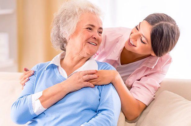 Eine Pflegerin lächelt eine ältere Dame an.