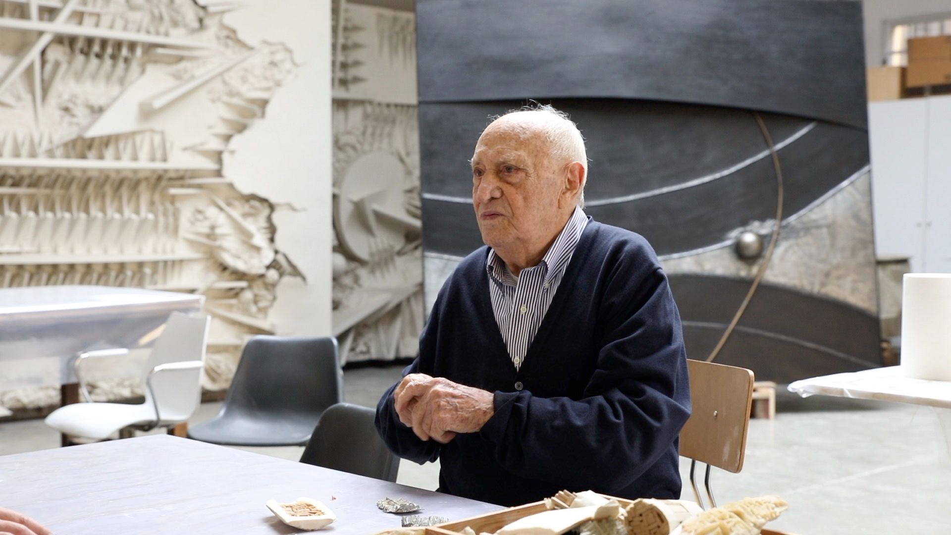 L'artista italiano Arnaldo Pomodoro siede davanti all'opera L'inizio del tempo