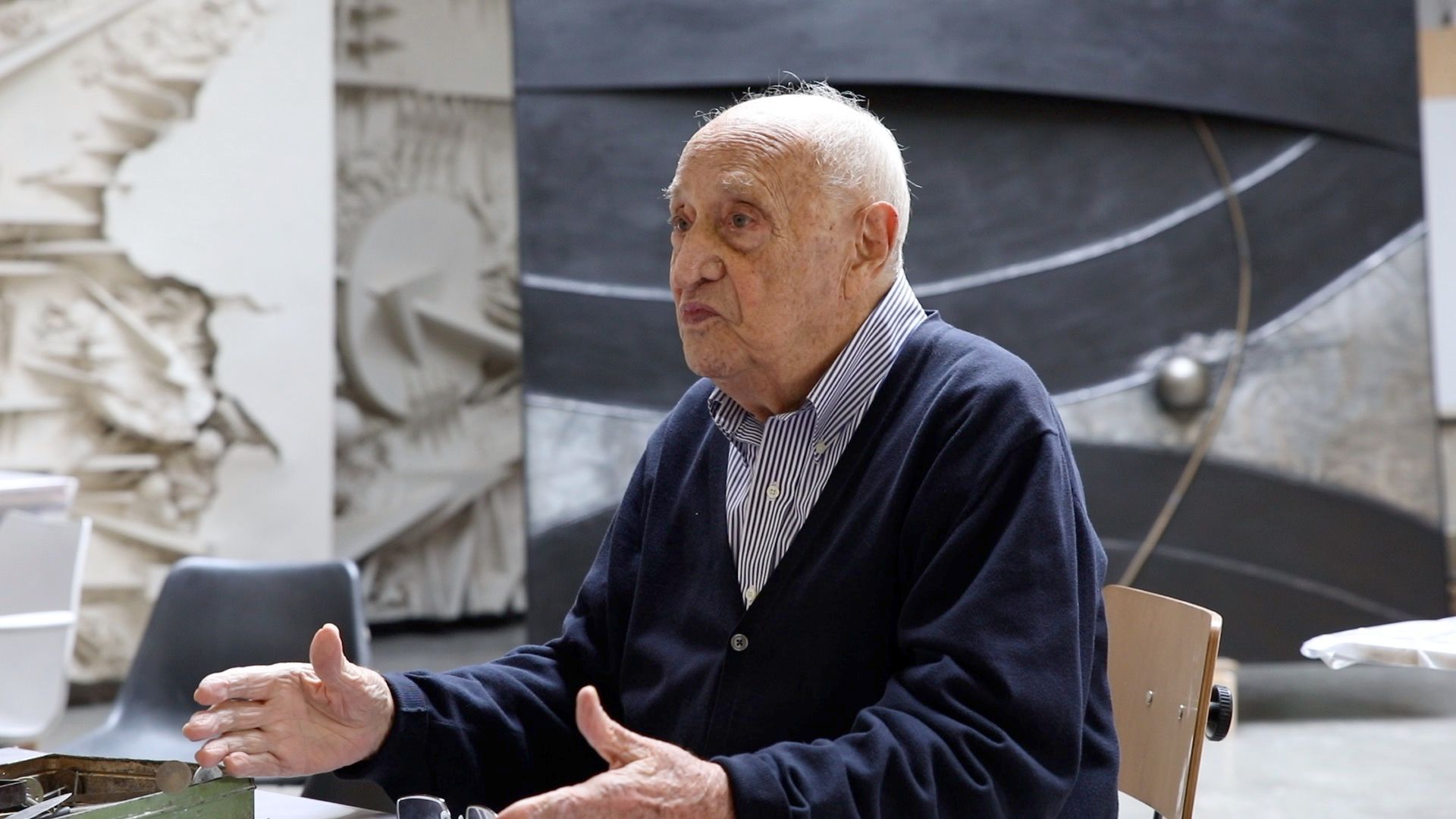 L'artista italiano Arnaldo Pomodoro siede davanti all'opera L'inizio del tempo