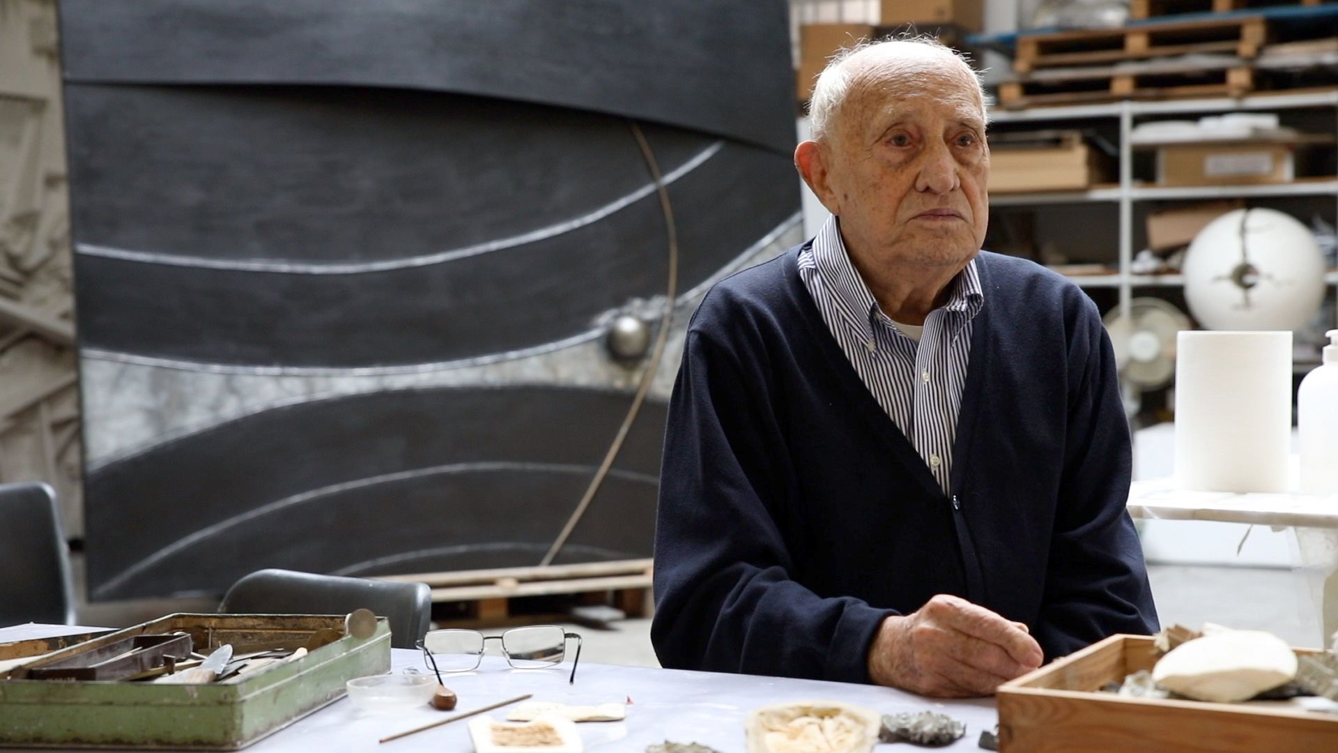 L'artista italiano Arnaldo Pomodoro siede davanti all'opera L'inizio del tempo