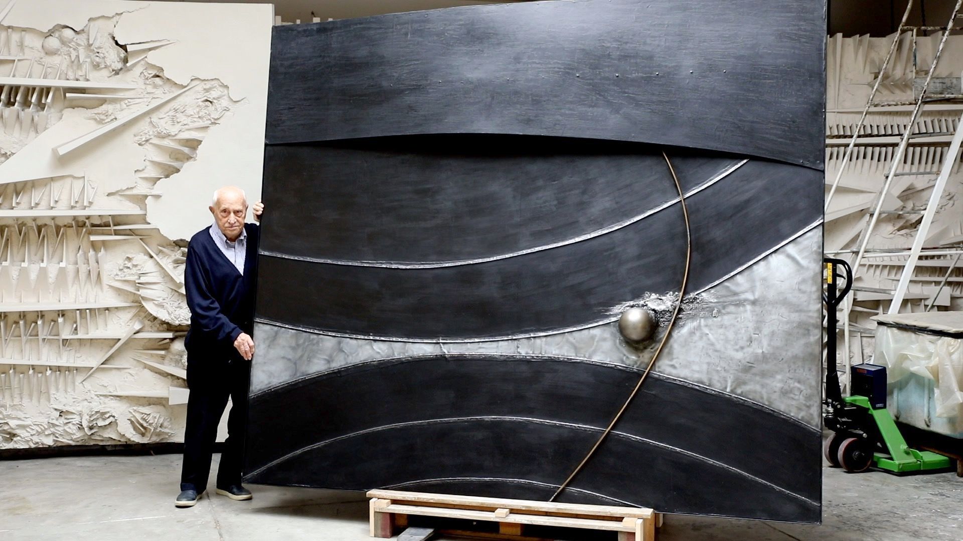 Der italienische Künstler Arnaldo Pomodoro steht vor dem Kunstwerk L'inizio del tempo