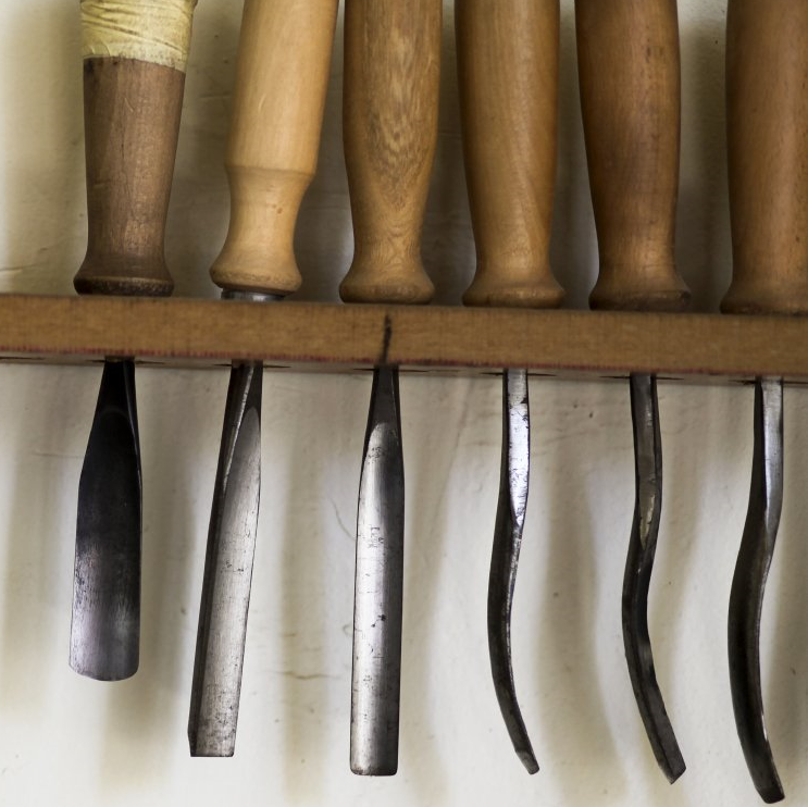 An image of wooden handles chisels hanging in a rack