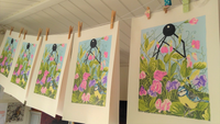 A photograph of four floral screen prints hanging on a line to dry in the studio