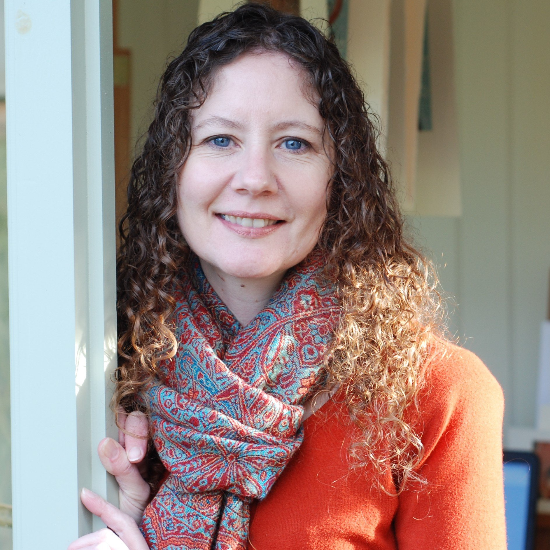 A photograph of the artist wearing a bright orange top