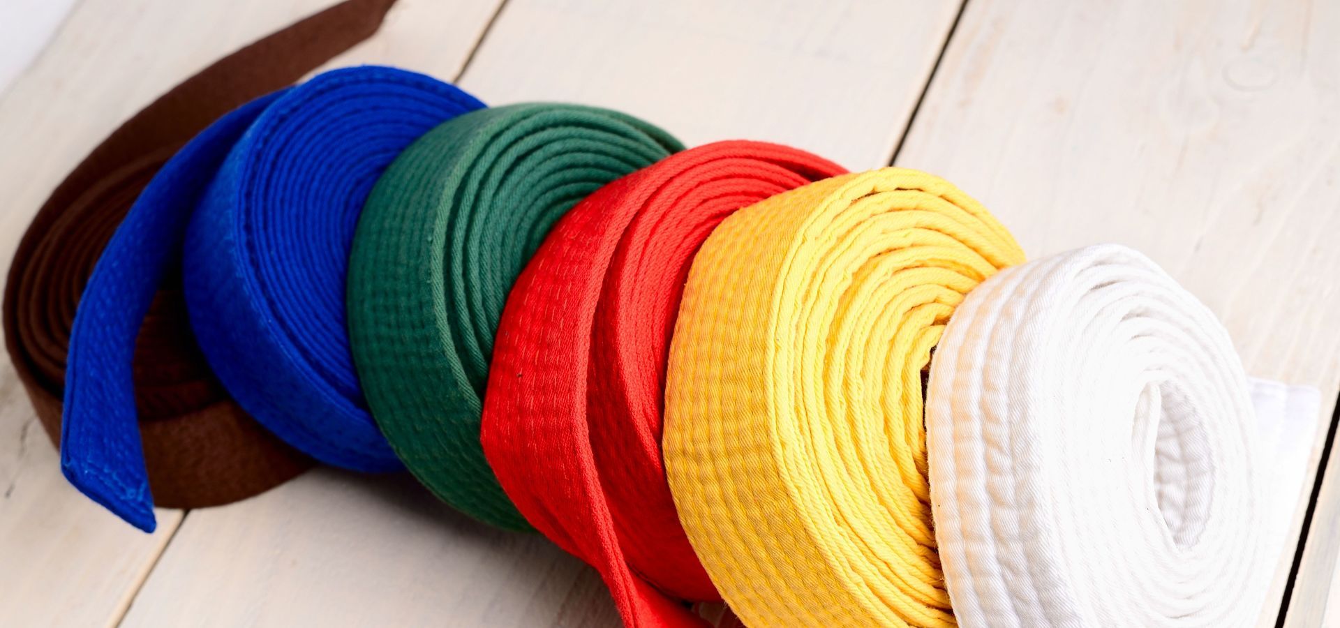 Karate jump kick in the air. Belt colors. Kids in karat. Uniform and Gi on floor. Friends at karate tournamemt.