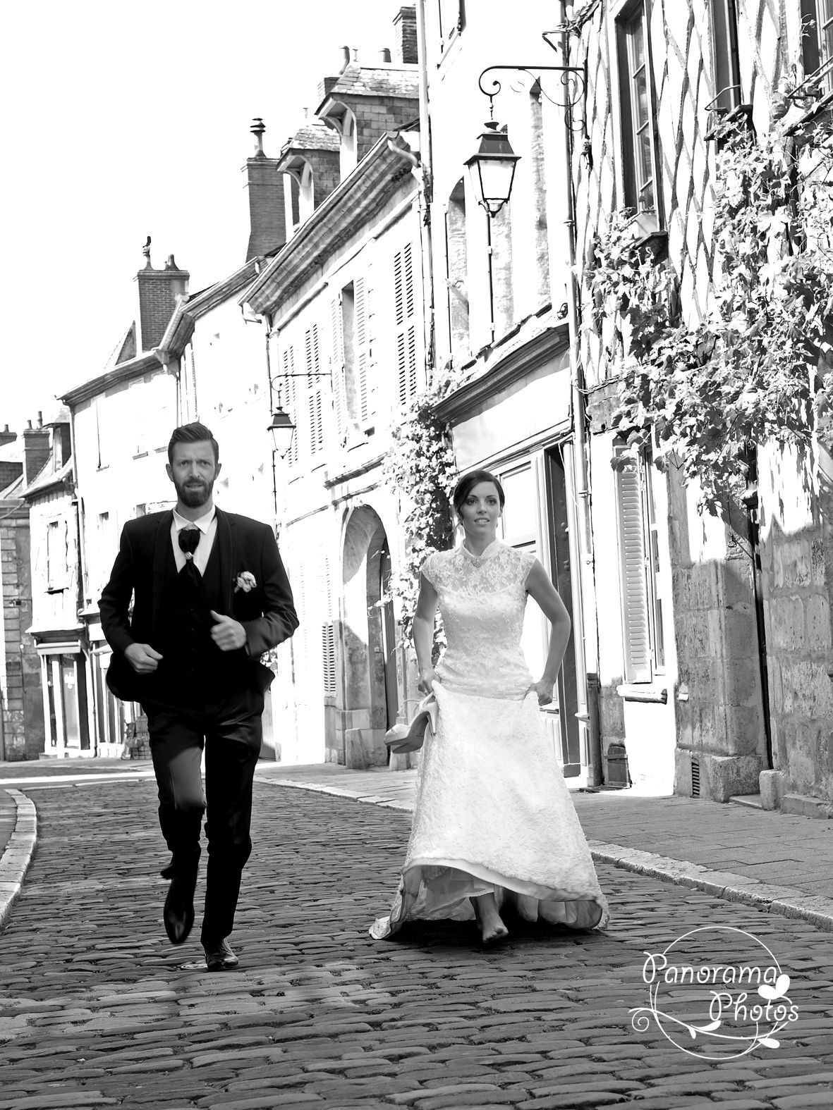 photo de mariage montrant un couple de mariés qui court dans une vielle rue pavée