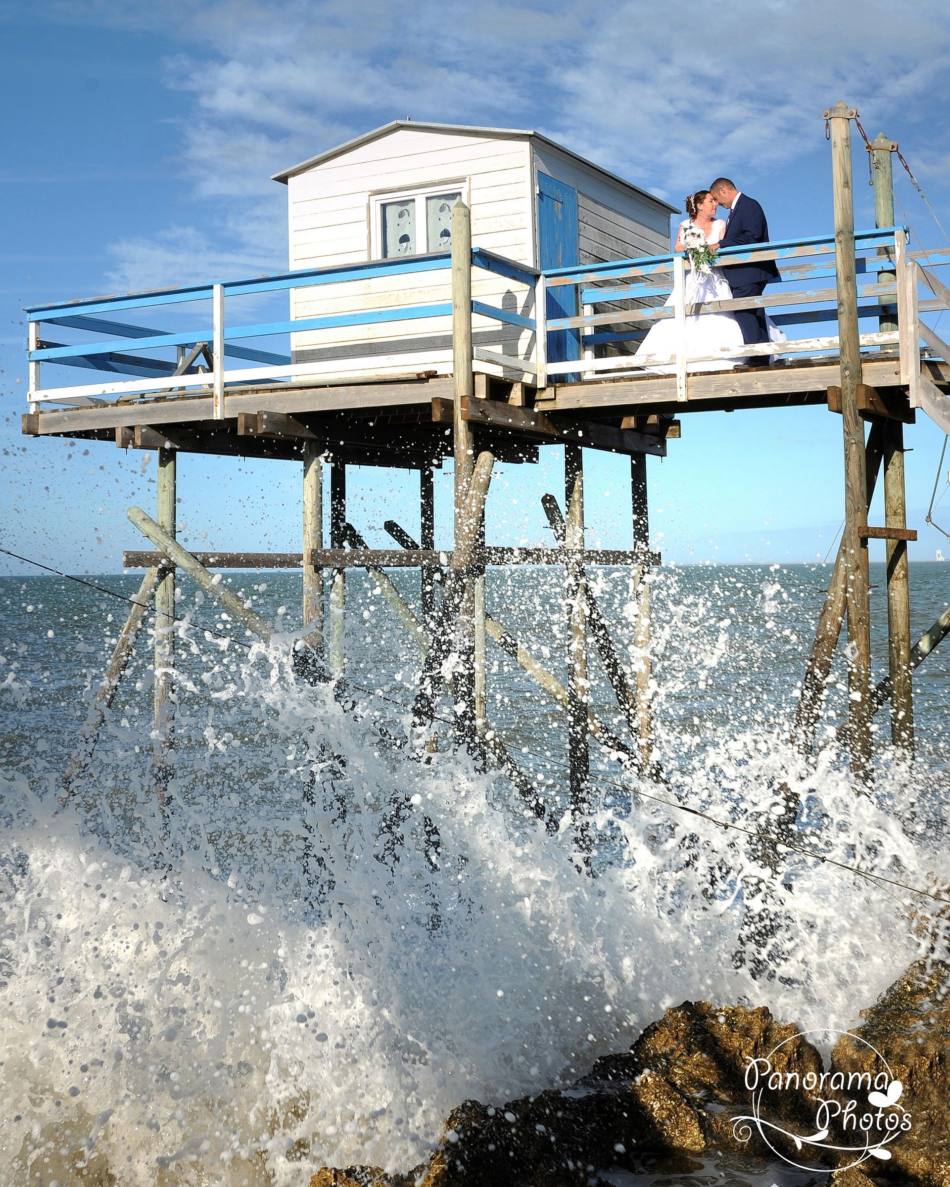 photo de mariage montrant des mariés sur une maison de pécheur dans une vague