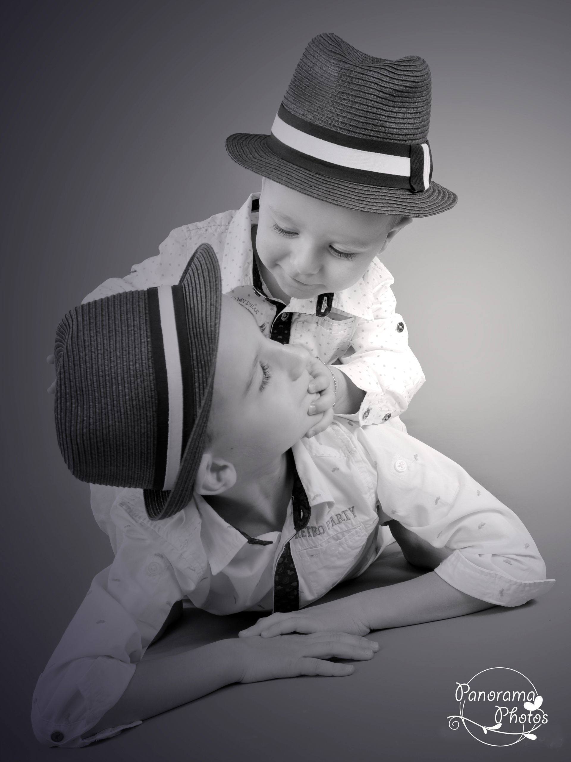 séance photo studio famille deux garçons assis l'un sur l'autre avec chapeau
