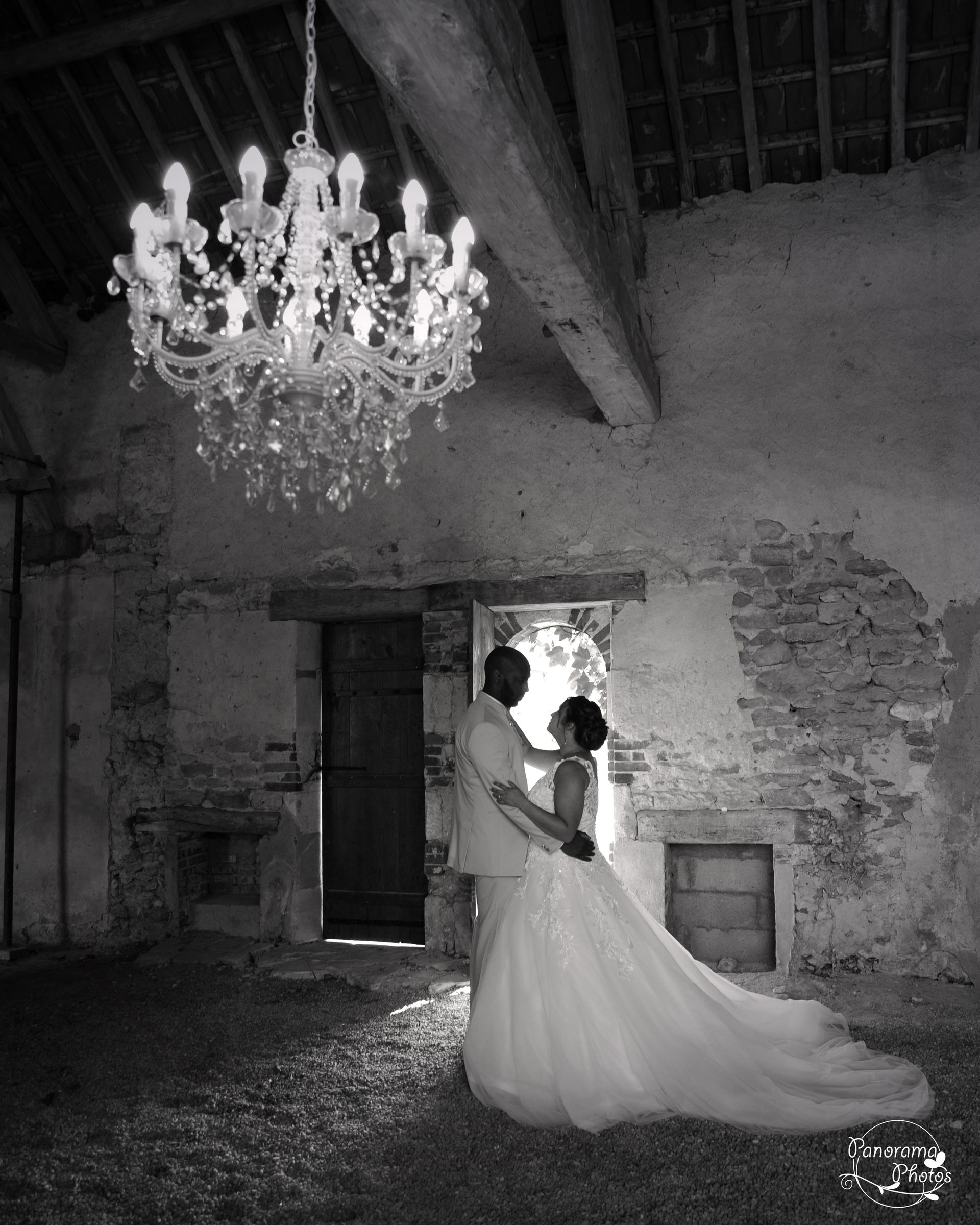 couple de marié dans une grange s'embrassant sous un lustre baroque