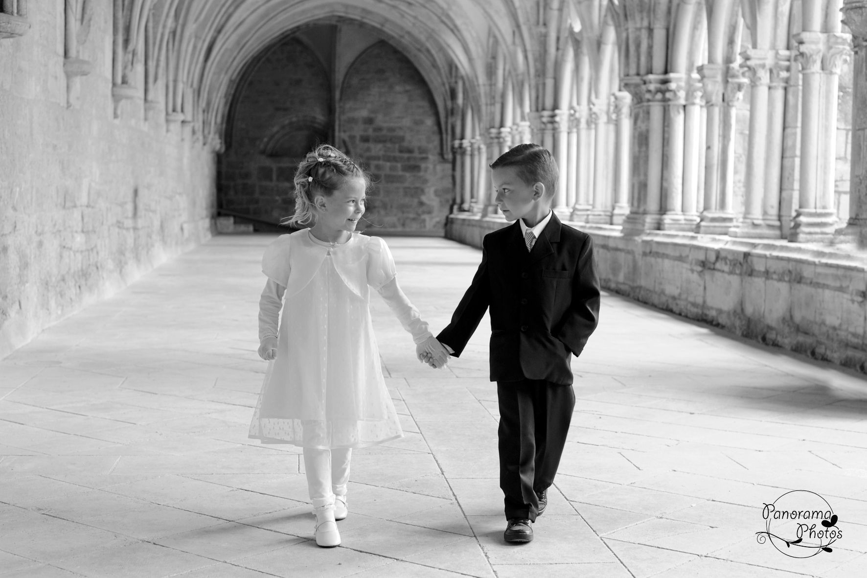 photo de mariage montrant des enfants en tenue de mariés marchant dans le cloitre d'une abbaye