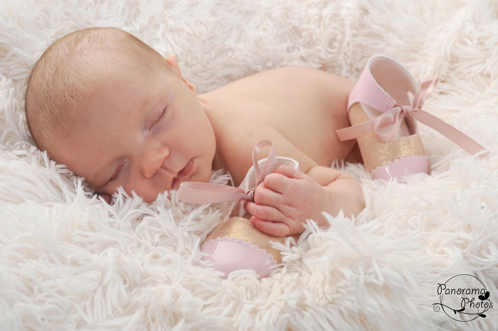 séance photo studio nouveau né qui tient une paire de chaussons
