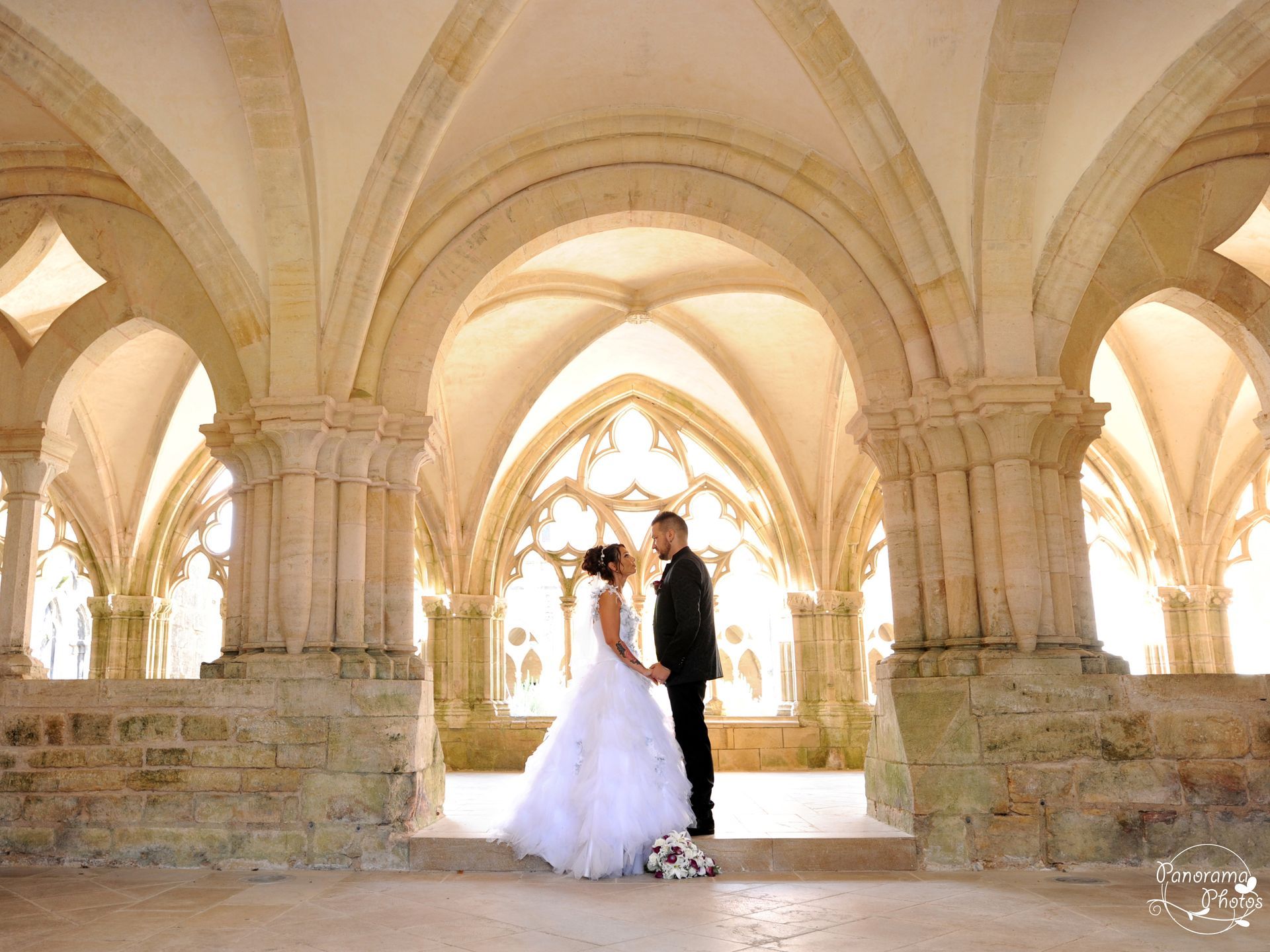 photo de mariage montrant des mariés sous une arche d'une abbaye