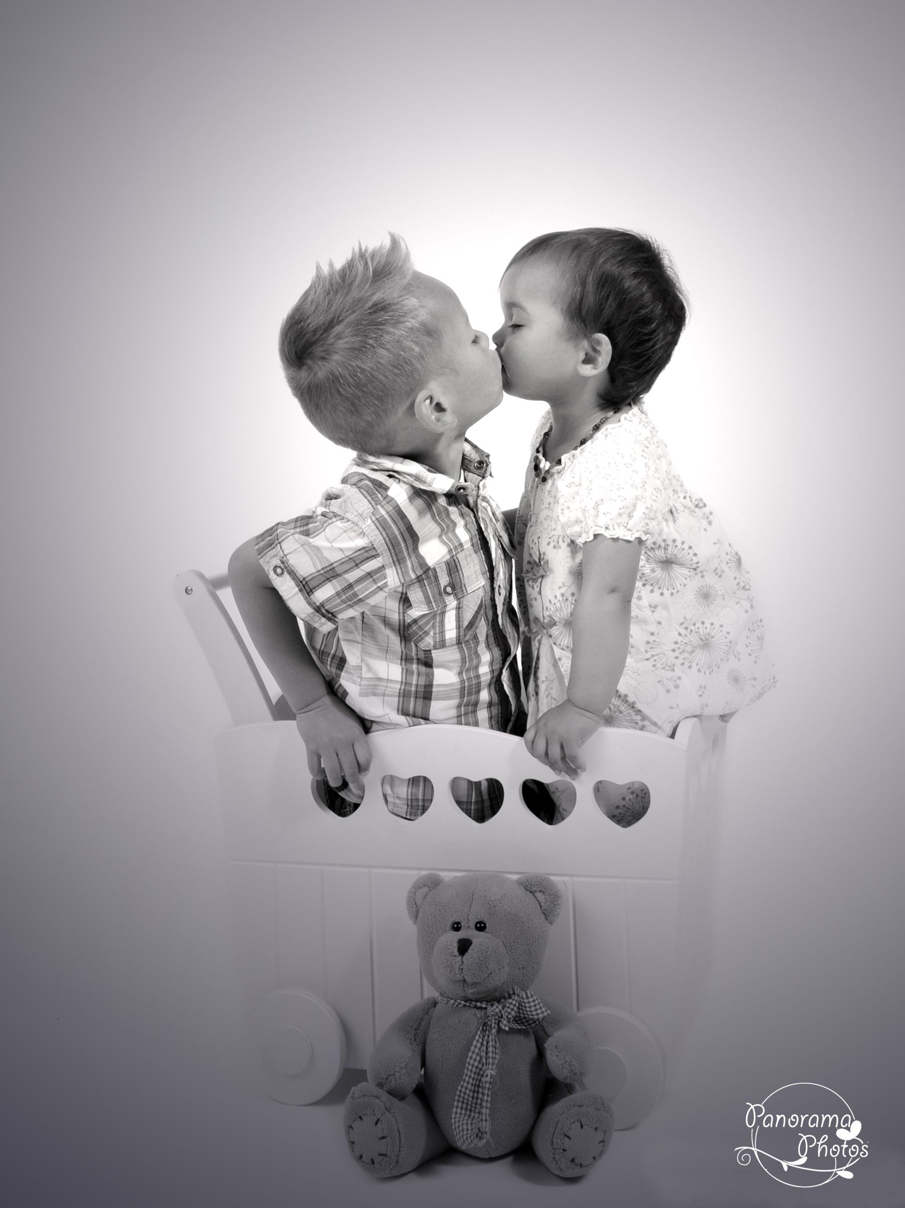 séance photo studio deux enfant qui s'embrassent dans un chariot en bois