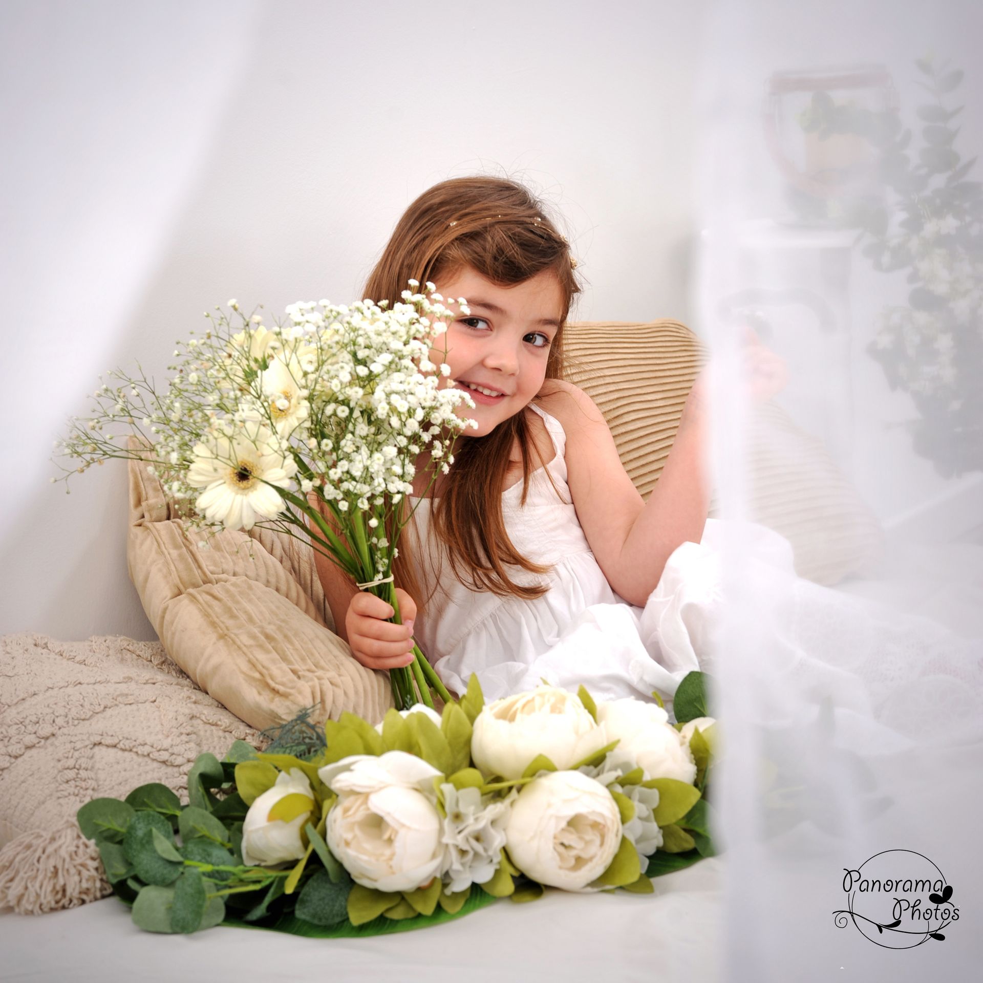petite fille avec un bouquet sur un lit derrière des rideaux