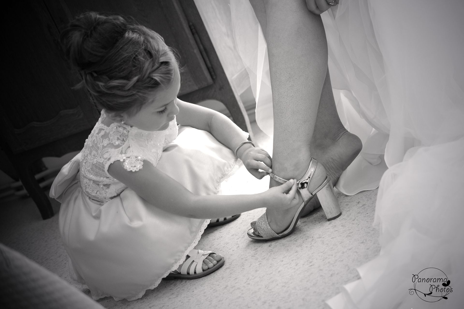 petite fille qui attache la chaussure de la mariée