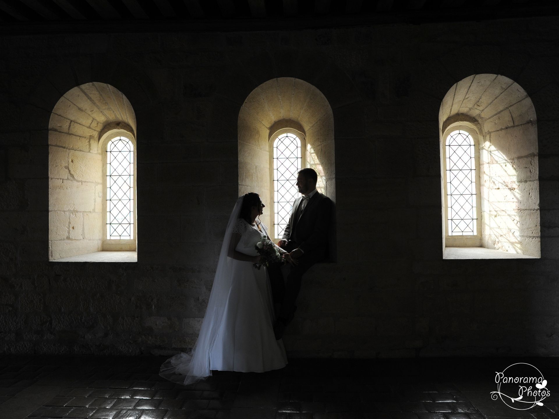 couple de marié en contre jour devant une lucarne d'une abbaye