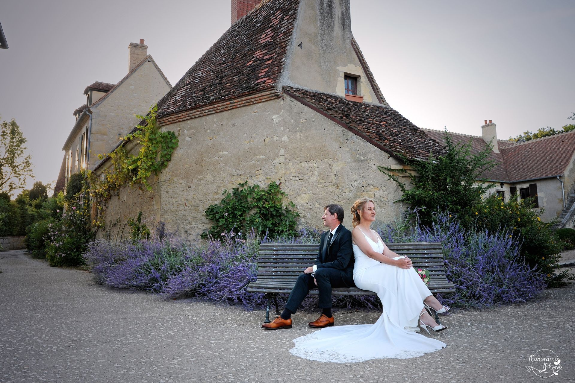 couple de marié assis sur un banc dos à dos devant des lavandes
