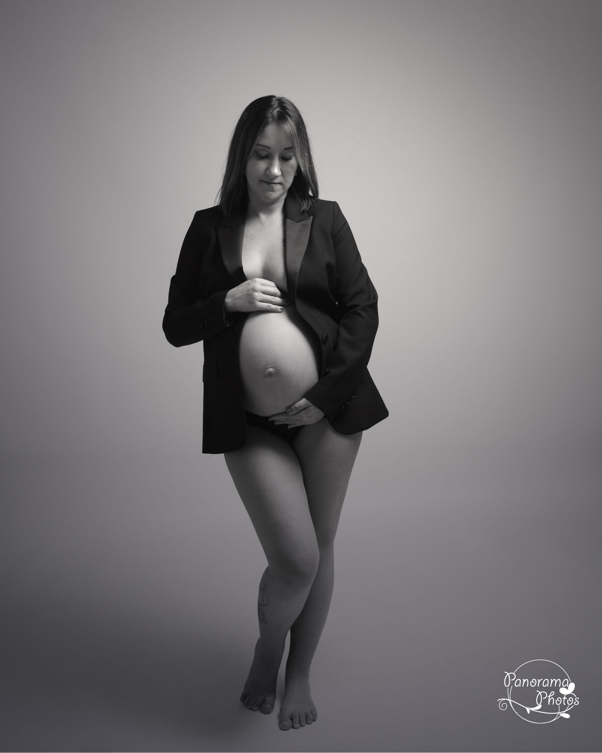 Photo en noir et blanc d'une femme enceinte avec une veste de tailleur ouverte