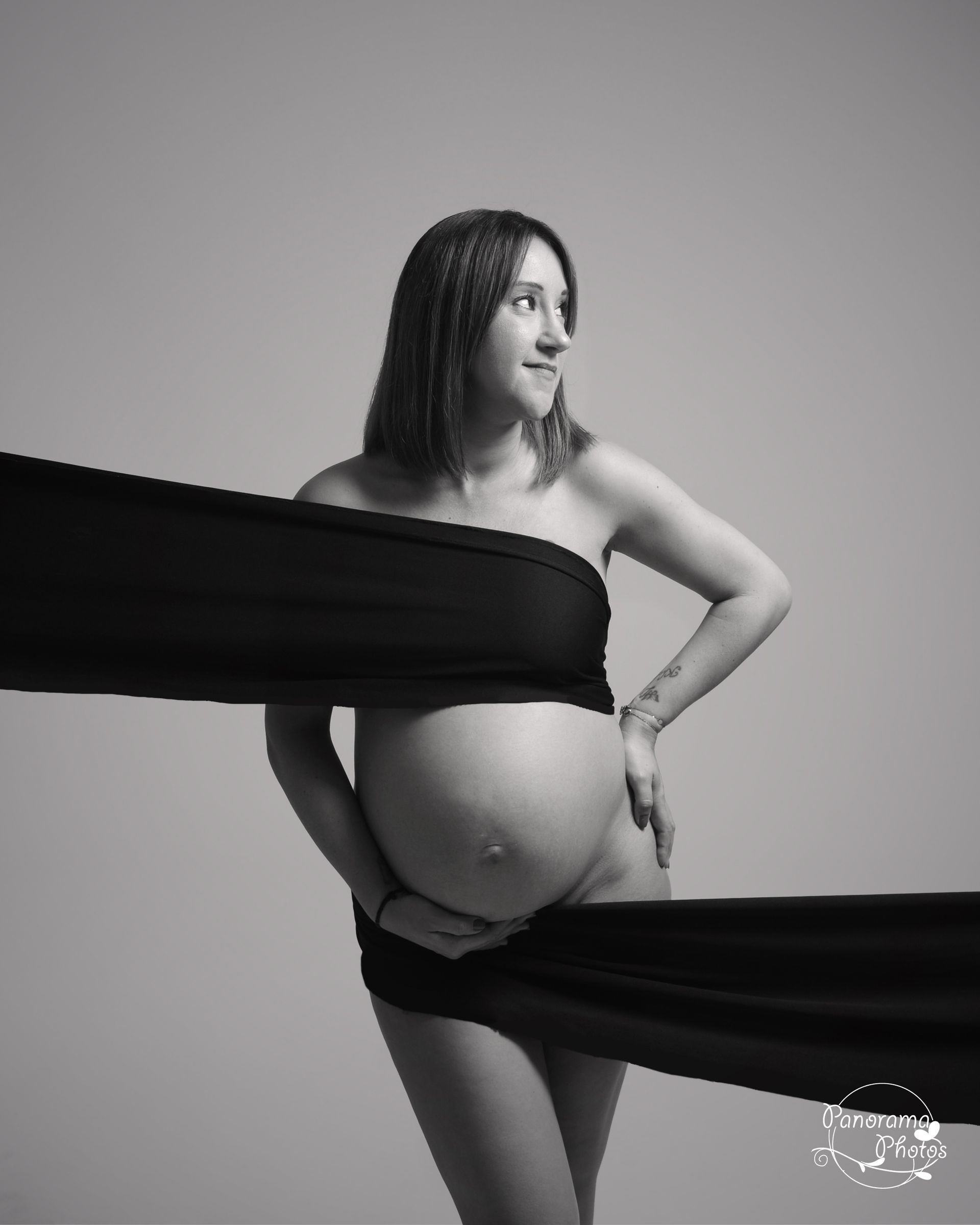 Photo en noir et blanc d'une femme enceinte entouré d'un tissu noir
