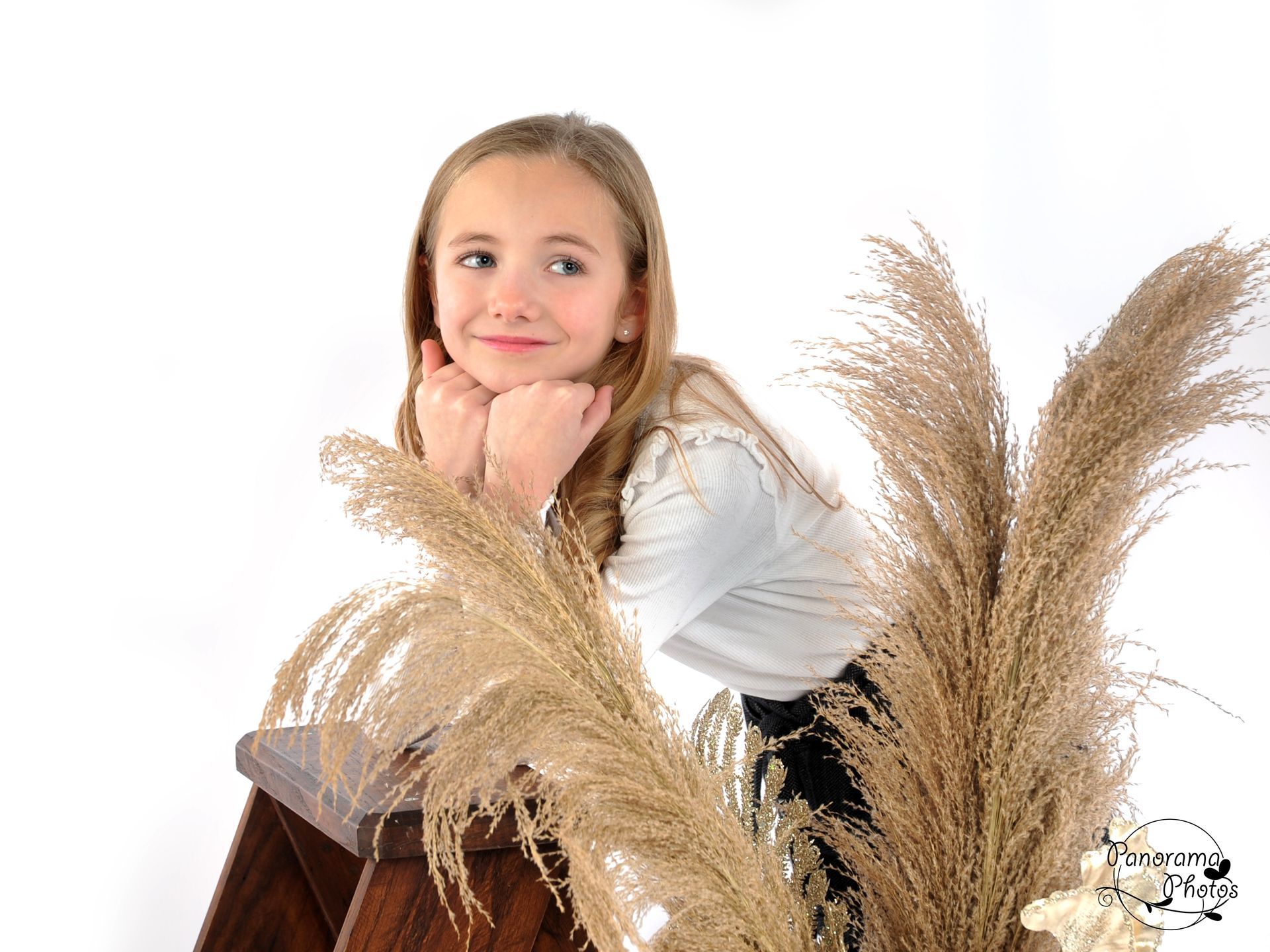 séance photo studio petite fille accoudée à un escabeau en bois