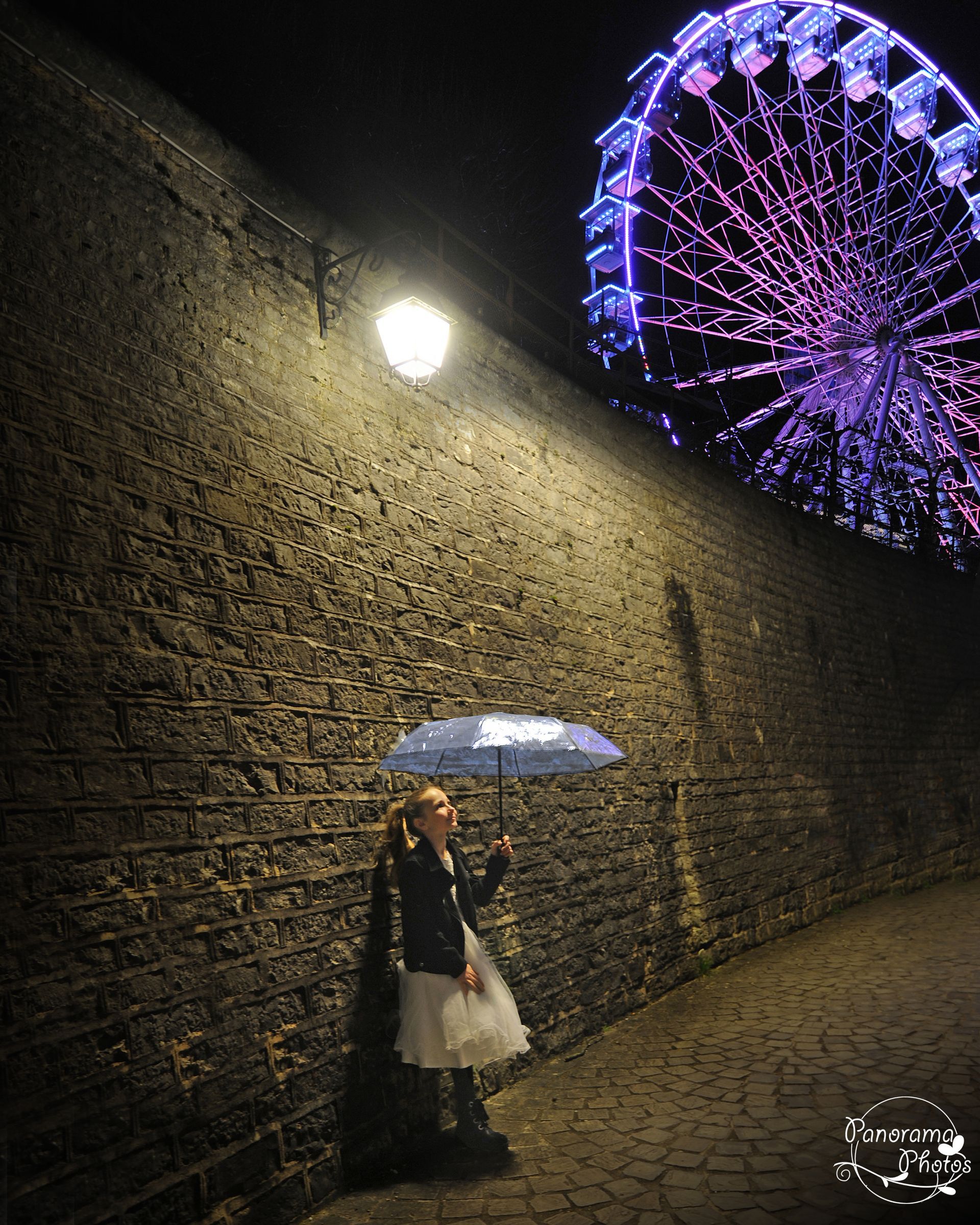 petite fille sous un parapluie de nuit avec grande roue en arrière plan