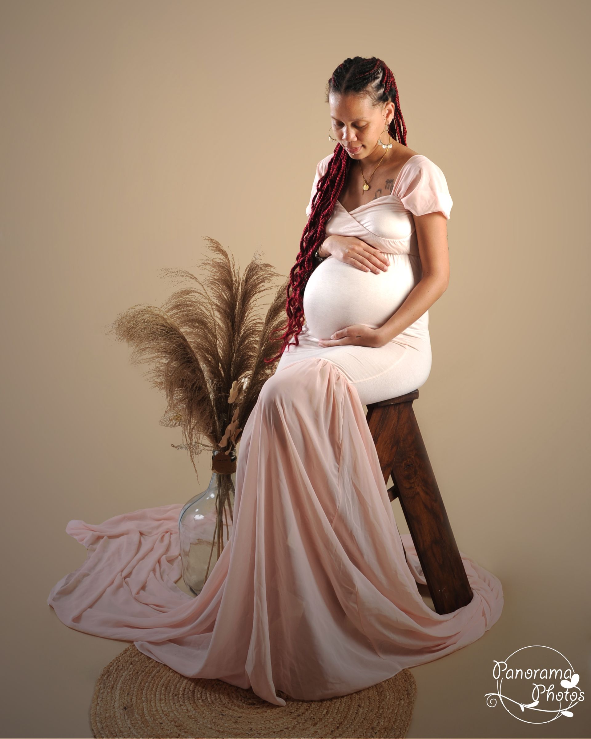 Photo d'une femme enceinte assise sur un escabeau en bois