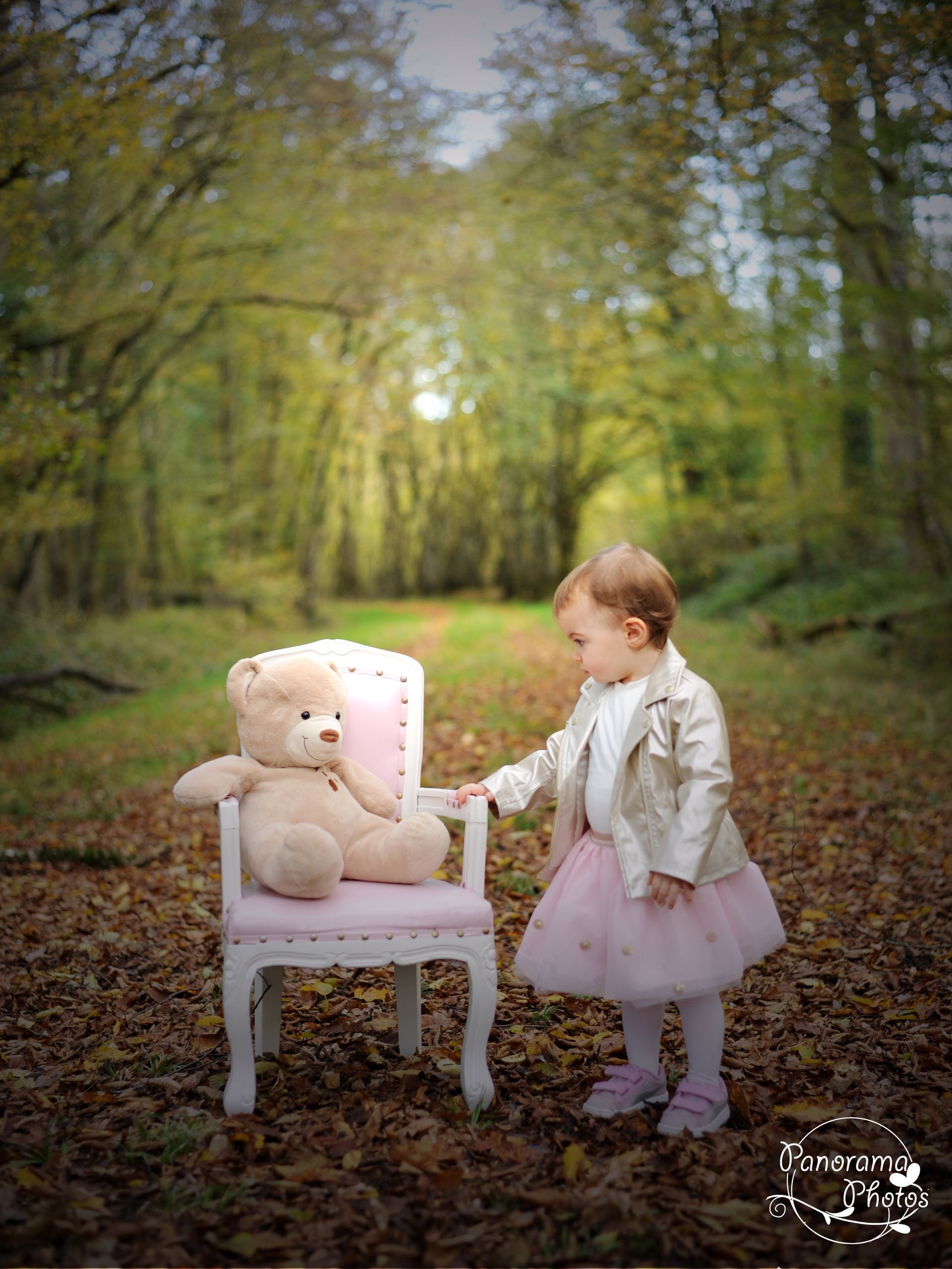 séance photo extérieure petite fille debout a coté d'un fauteuil dans une foret