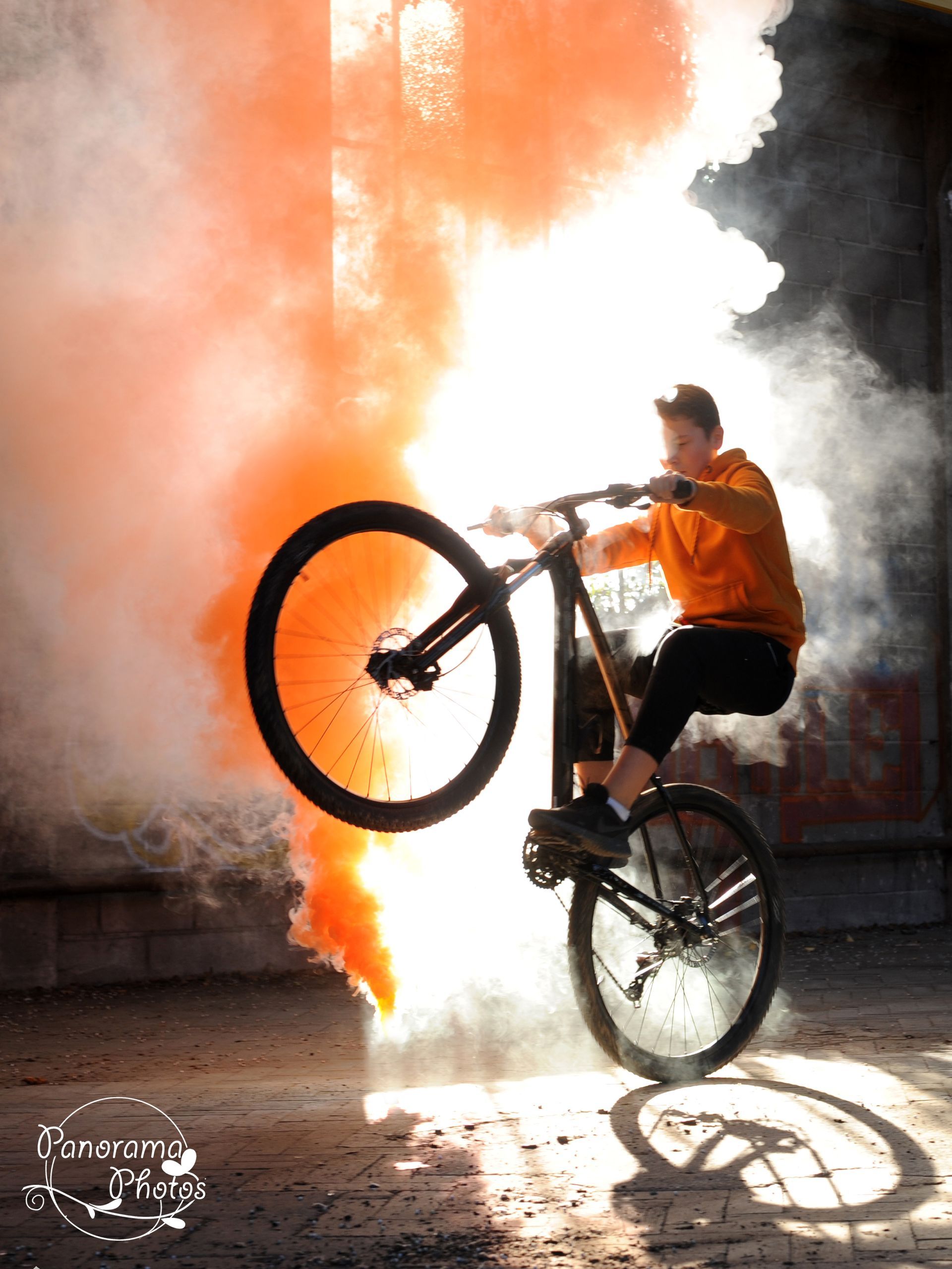 séance photo extérieure portrait dans une usine désaffectée d'un garçon sur son vélo avec fumigène