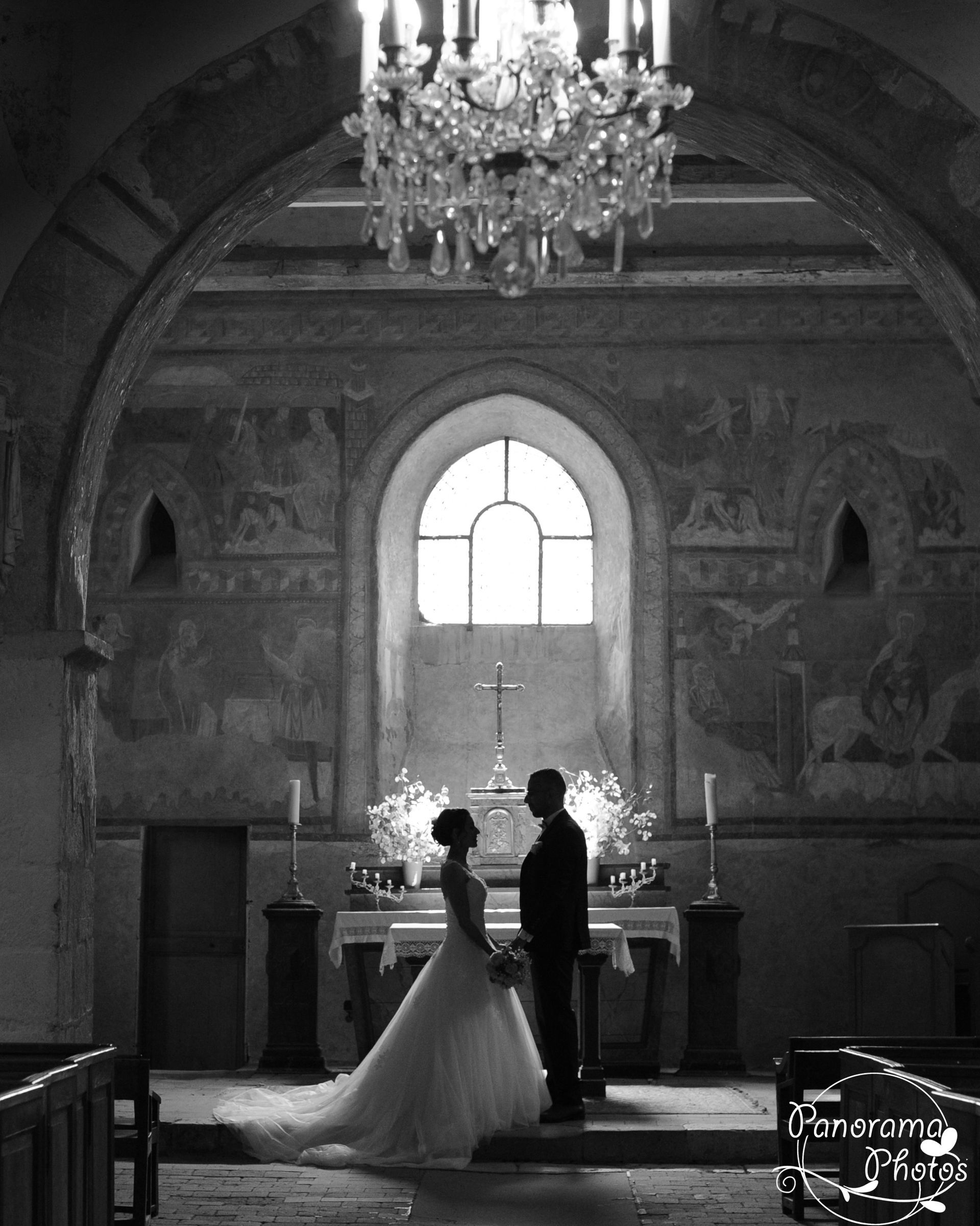 photo de mariage montrant un couple debout devant l'autel de l'église en contre jour