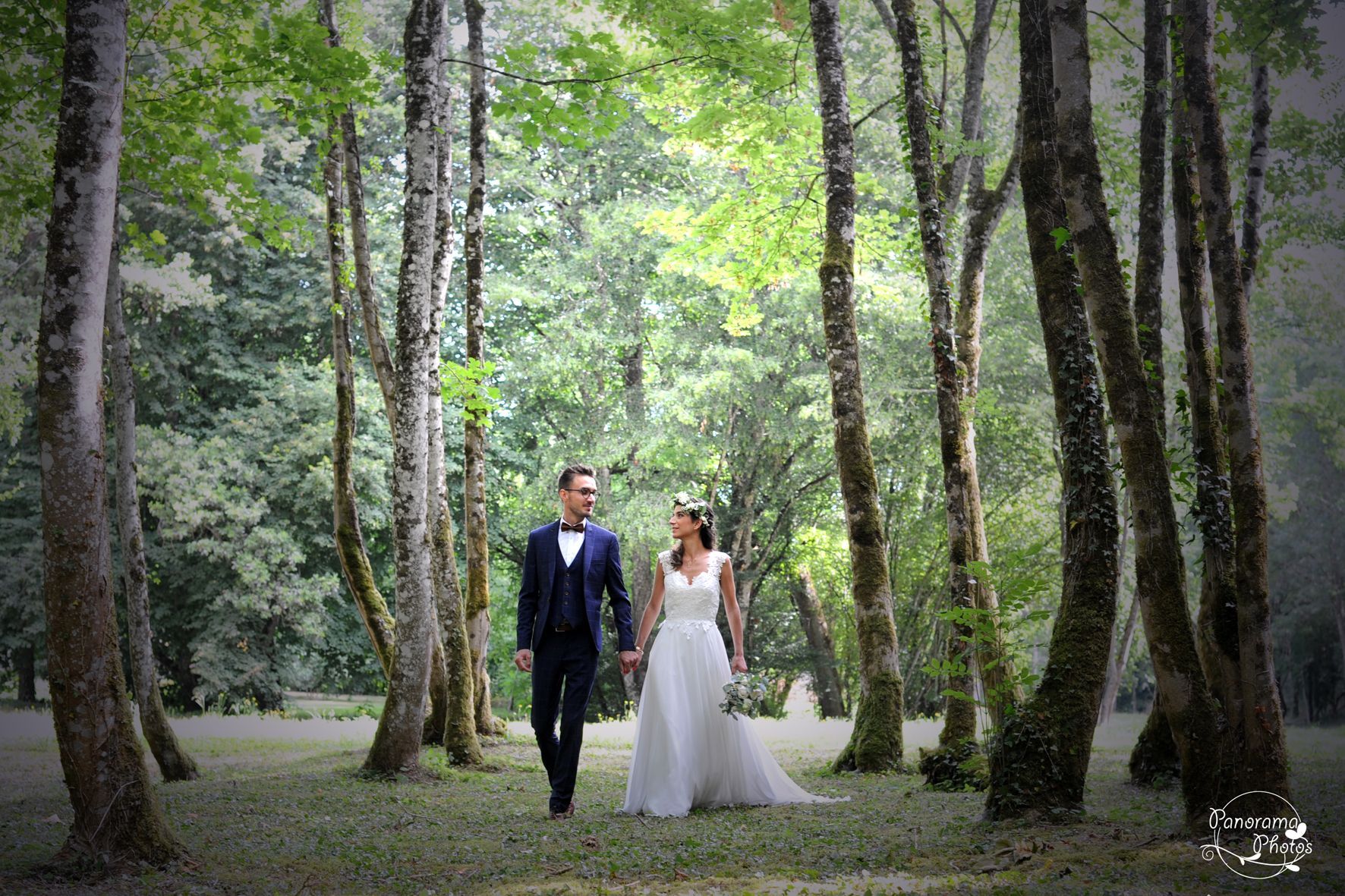 photo de mariage montrant un couple de mariés marchant dans la foret en se tenant la main