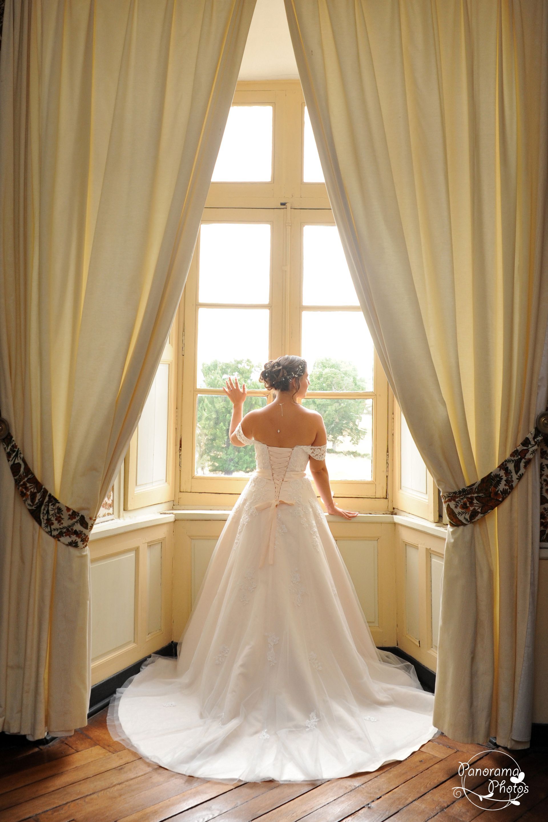 photo de mariage montrant une mariée regardant par la fenêtre