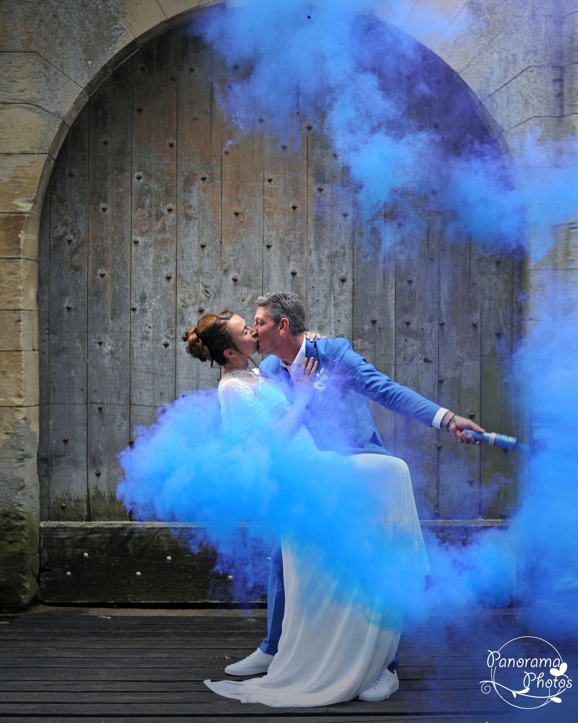 photo de mariage montrant des mariés s'embrassant dans des fumigènes bleus