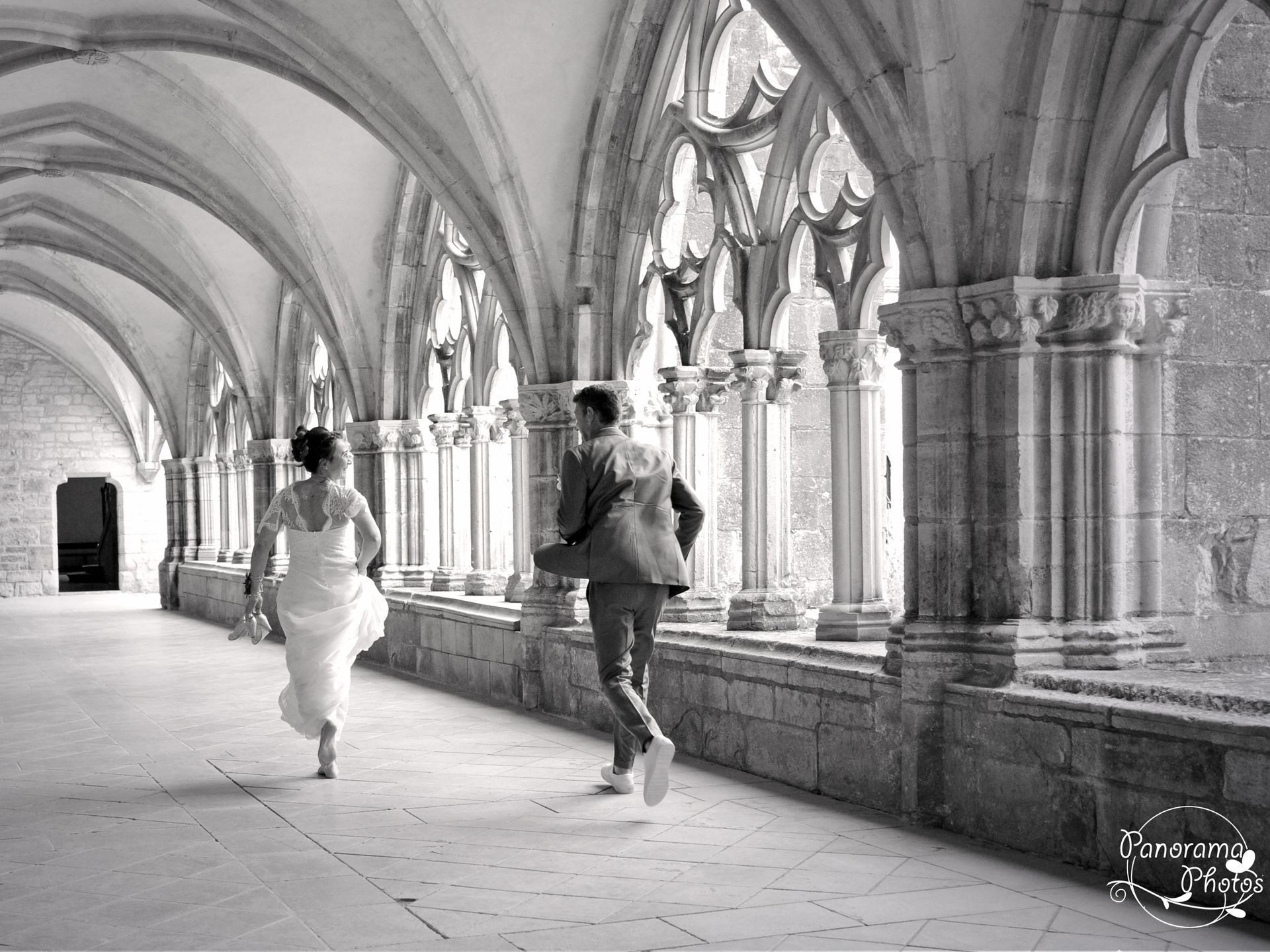 photo de mariage montrant un couple de mariés qui courent dans le cloitre d'une abbaye