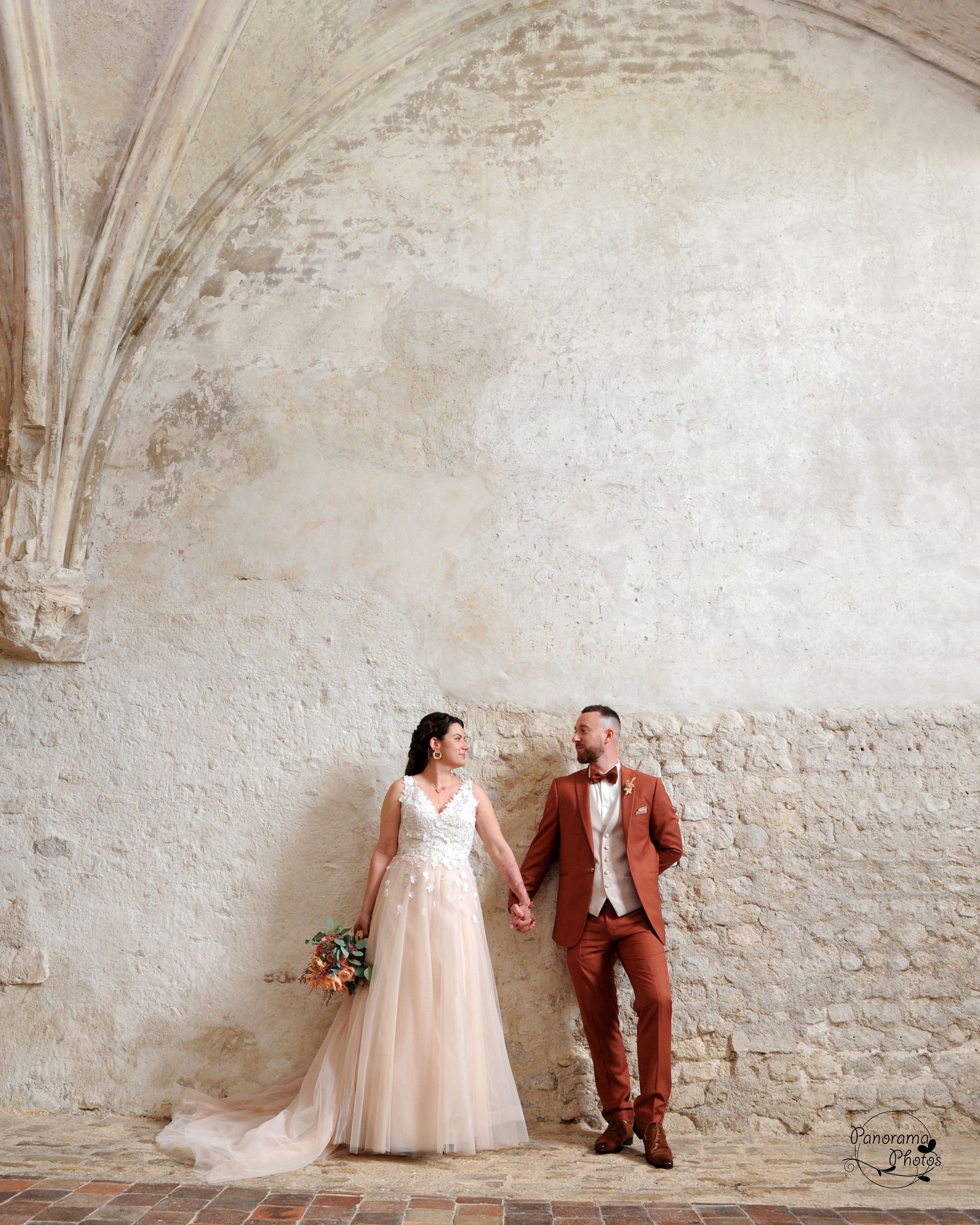 couple de marié appuyé sur un mur en pierre