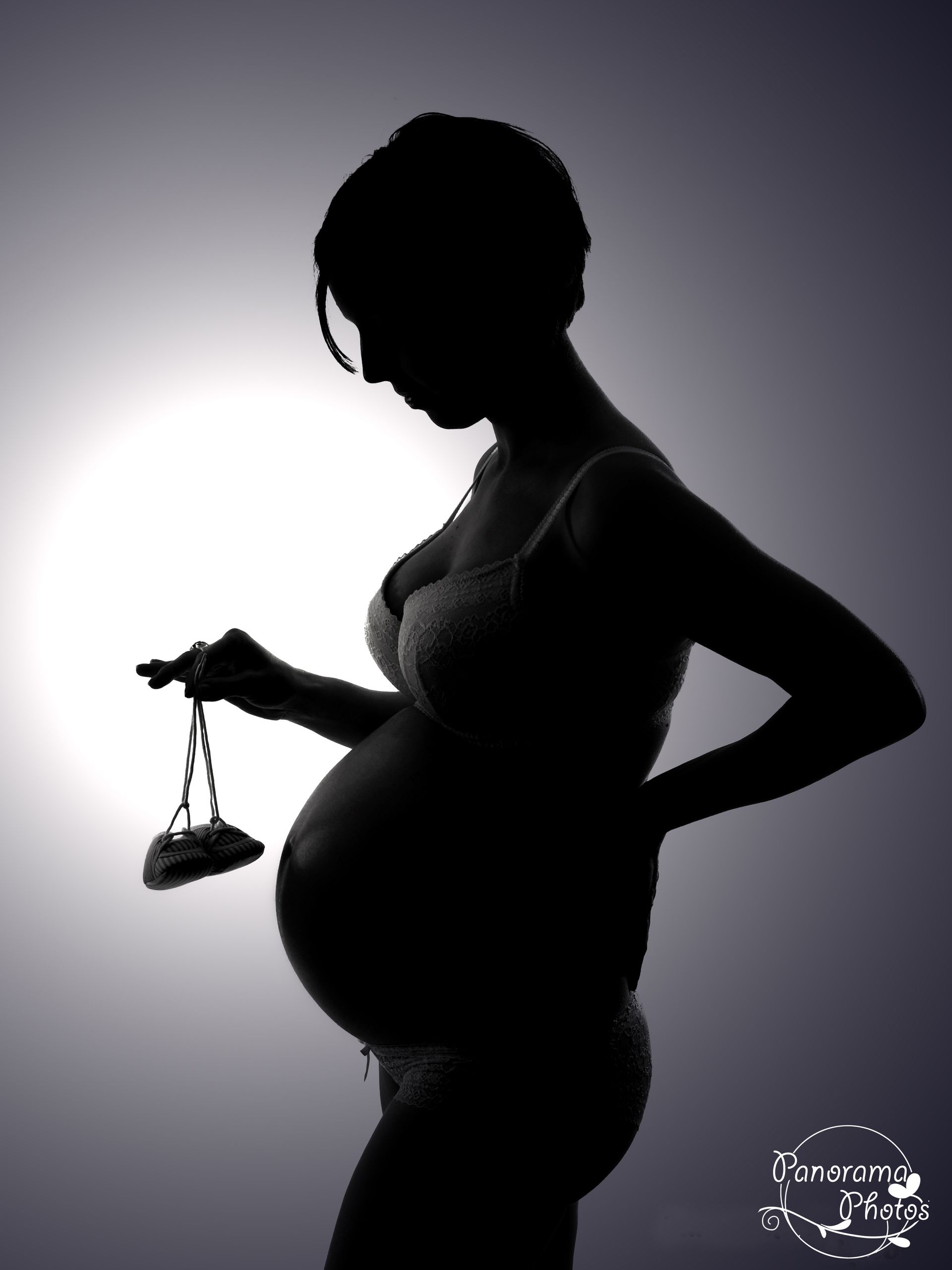 photo studio femme enceinte avec chausson de bébé en contre jour