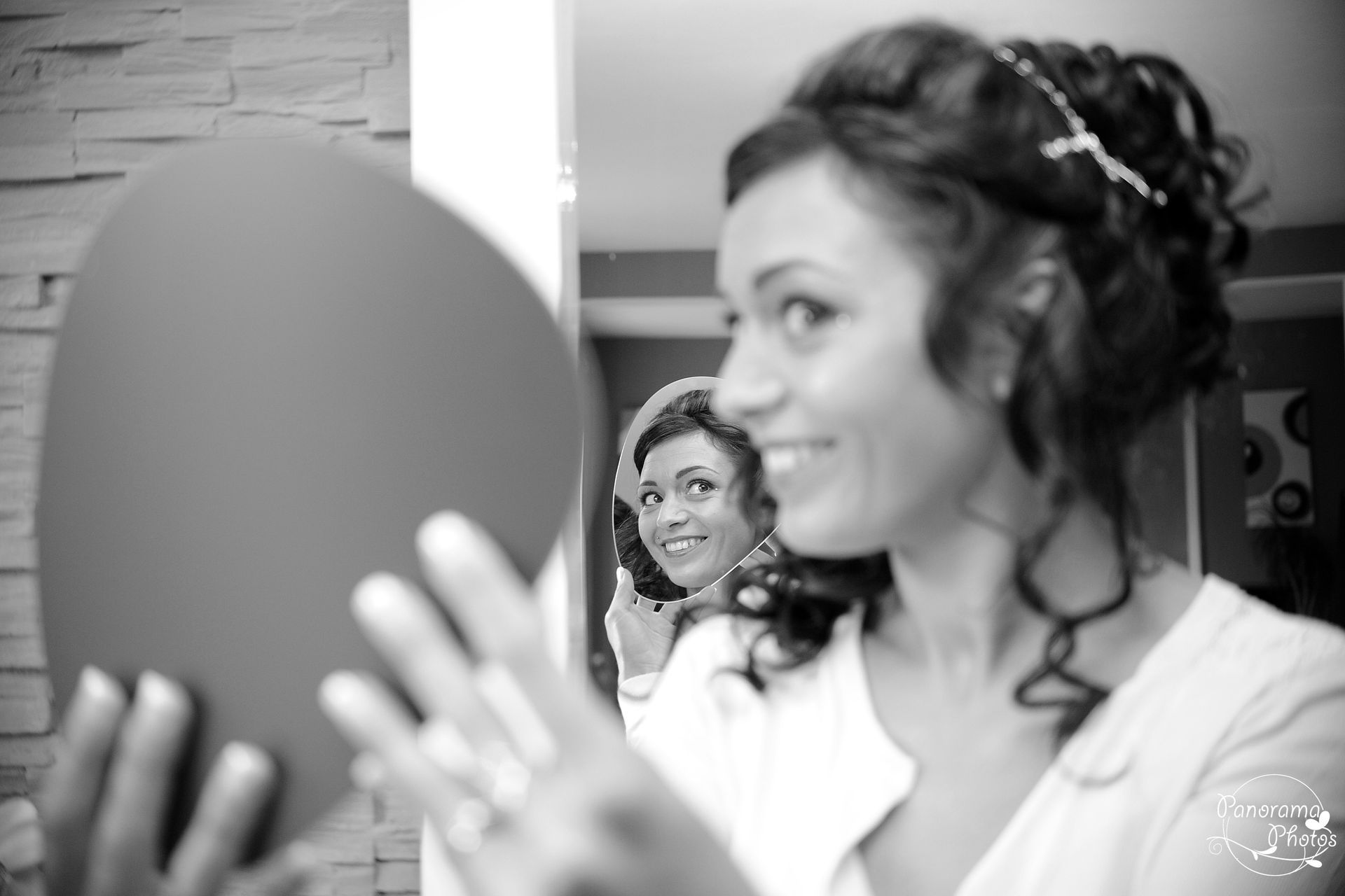 photo de mariage montrant une mariée qui se regarde dans le miroir en souriant