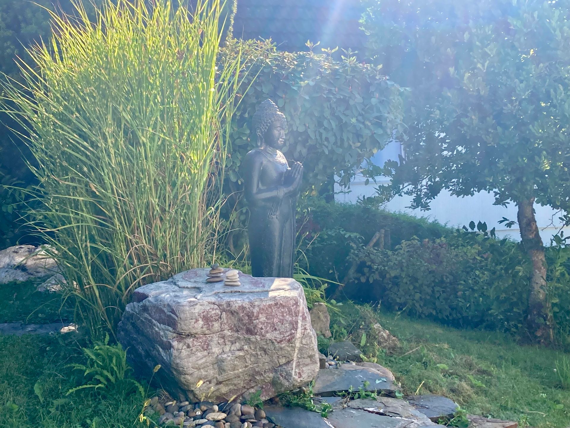 Ein Sonnenstrahl tirfft den Buddha im Garten der Stille.