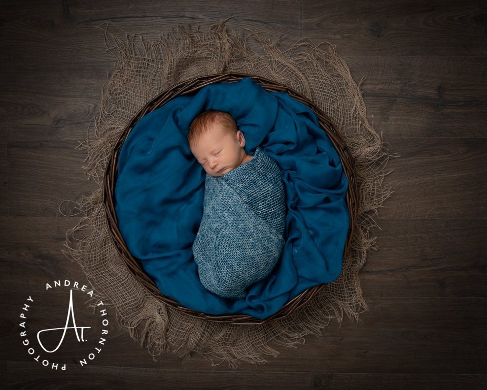 Sleeping baby boy in a basket wrapped in blue