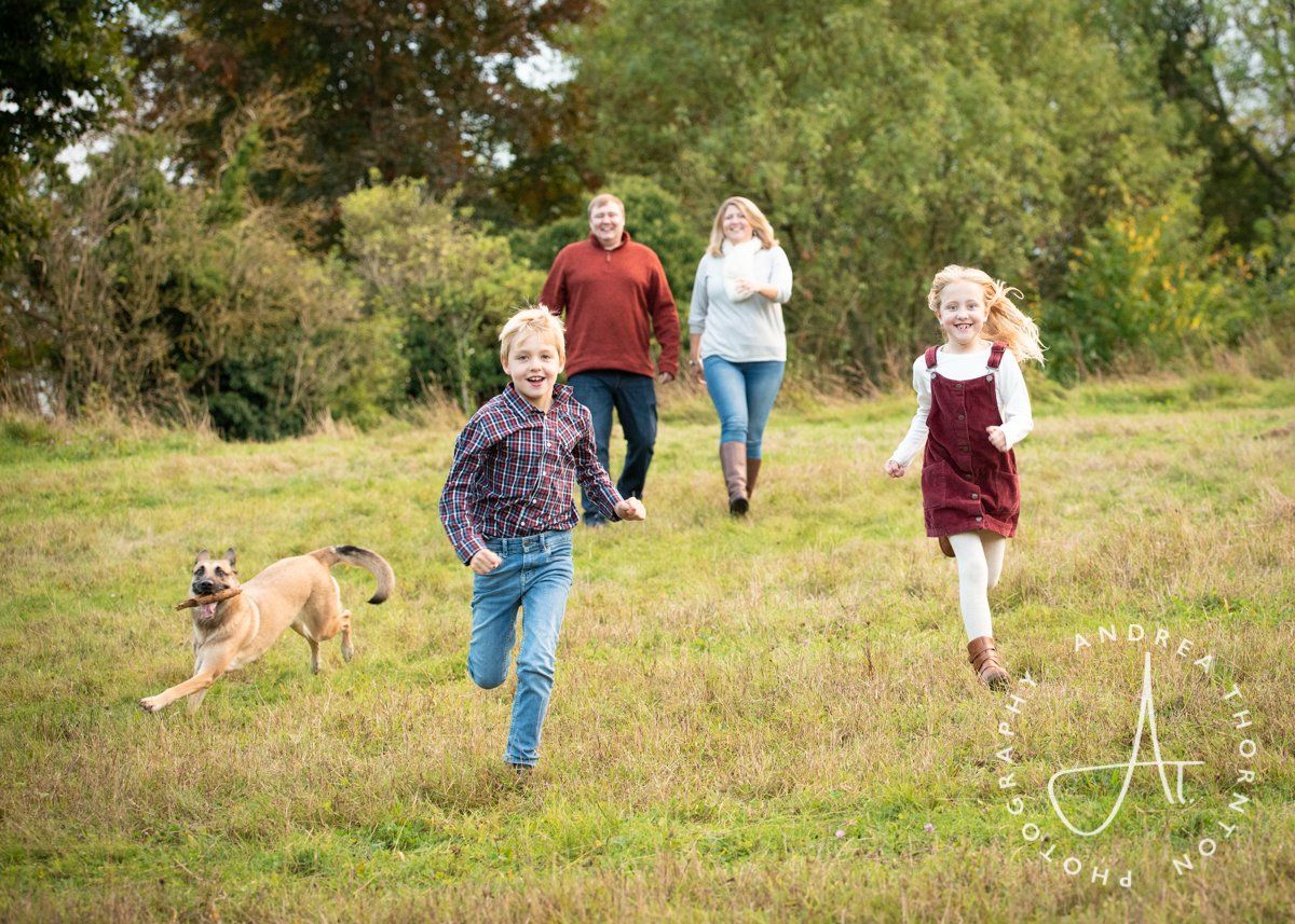 A smiling family of four walking and running outdoors