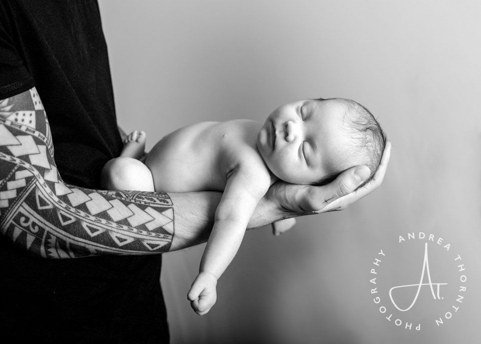 A relaxed newborn baby sleeping soundly in his father's arms