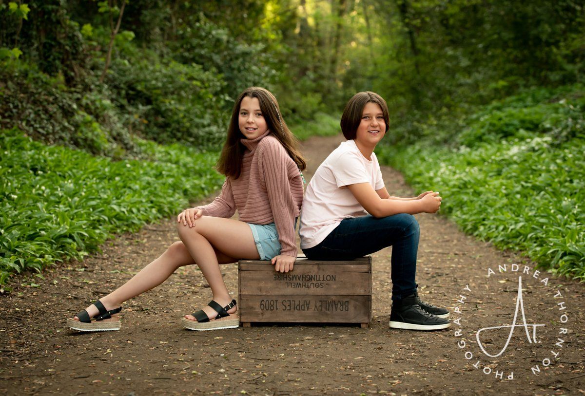 Siblings sitting on a woodland path during an outdoor family photoshoot