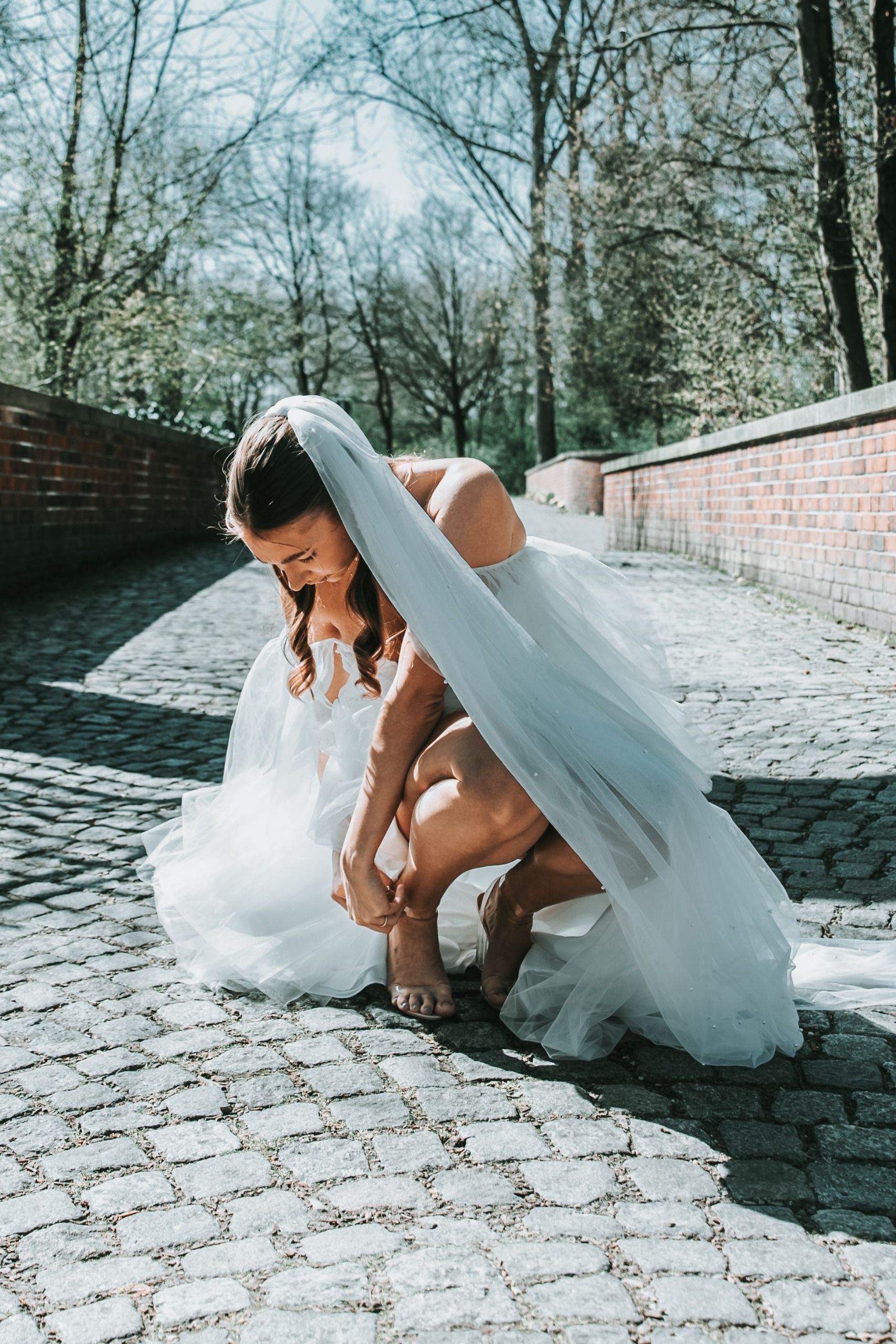 Auf dem Bild ist eine ästhetische Braut zu sehen, die ihren Schuh anzieht.