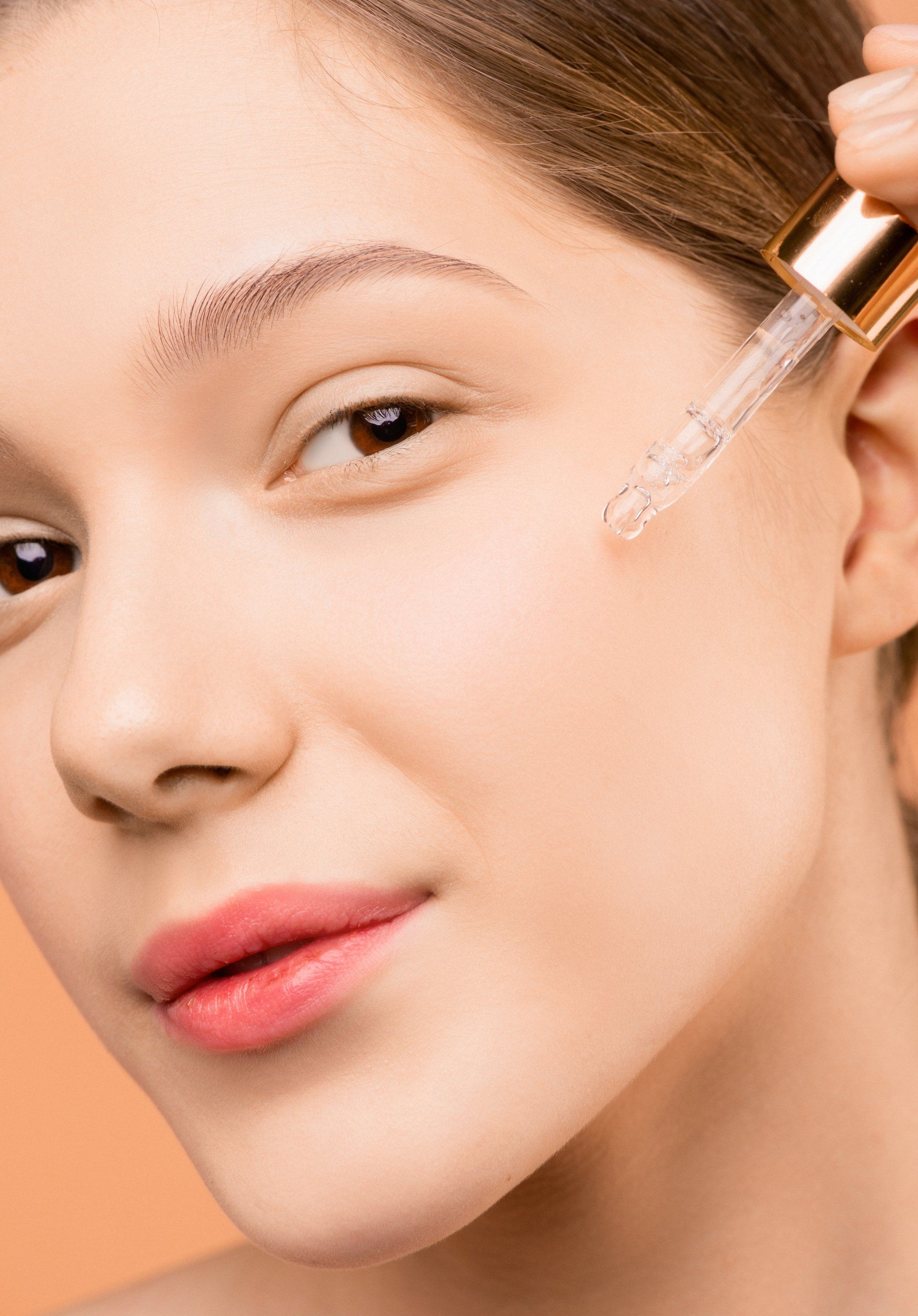 Girl using eyedropper to dispense oil onto face